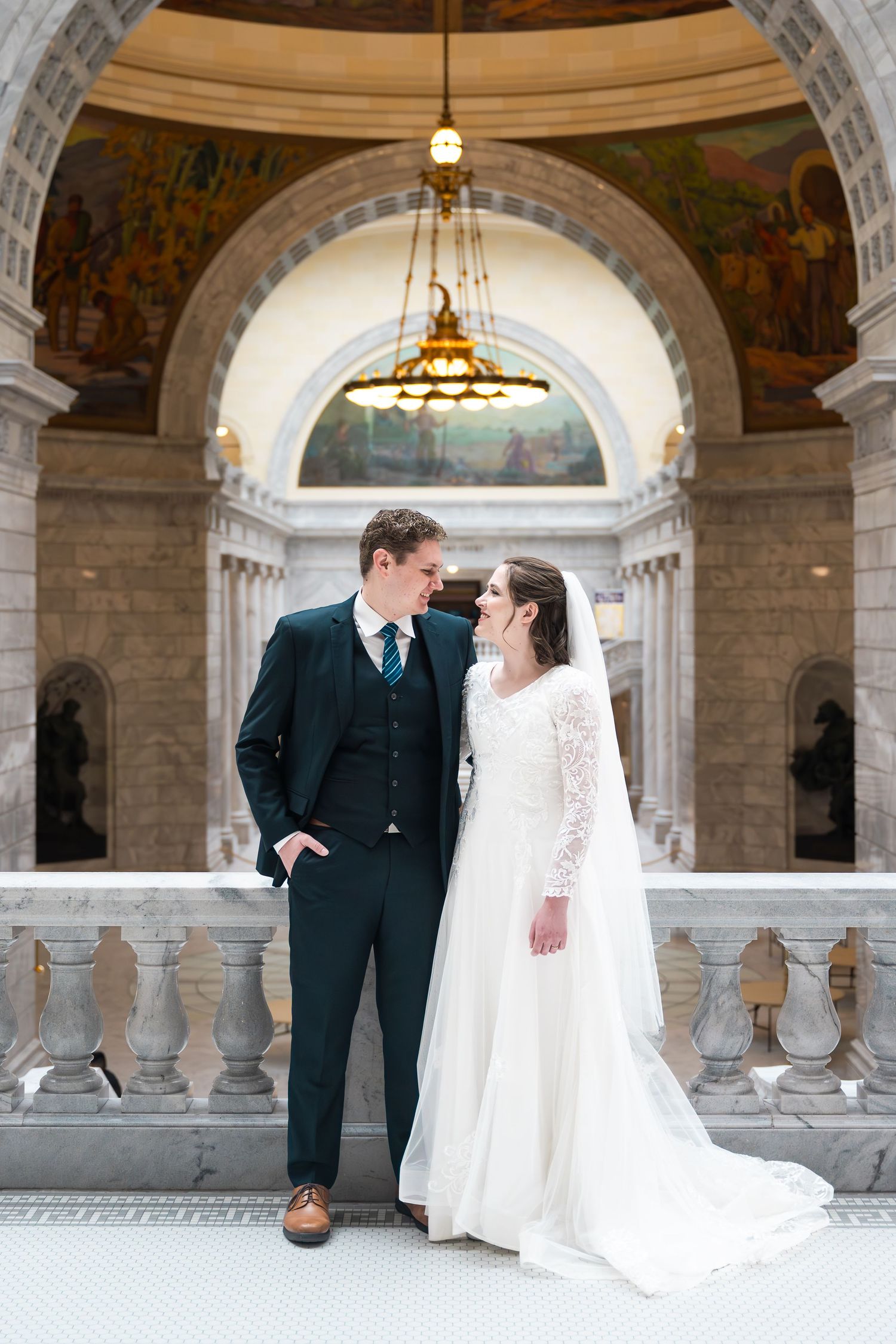 Bride and groom posing beneath the grand architecture of the State Capitol during timeless wedding portraits.