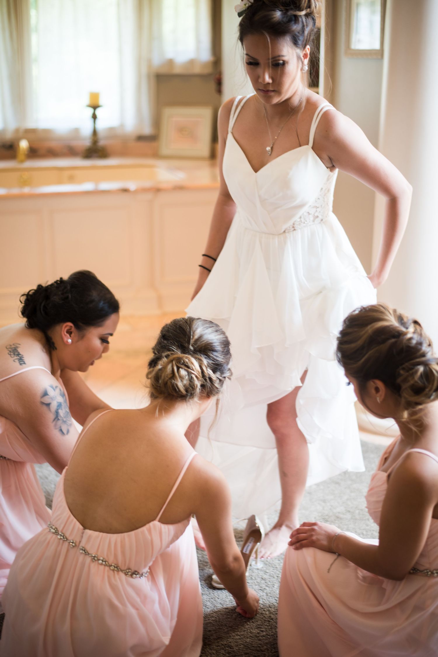 Wedding preparation moment featuring the bride and bridesmaids helping with final details.