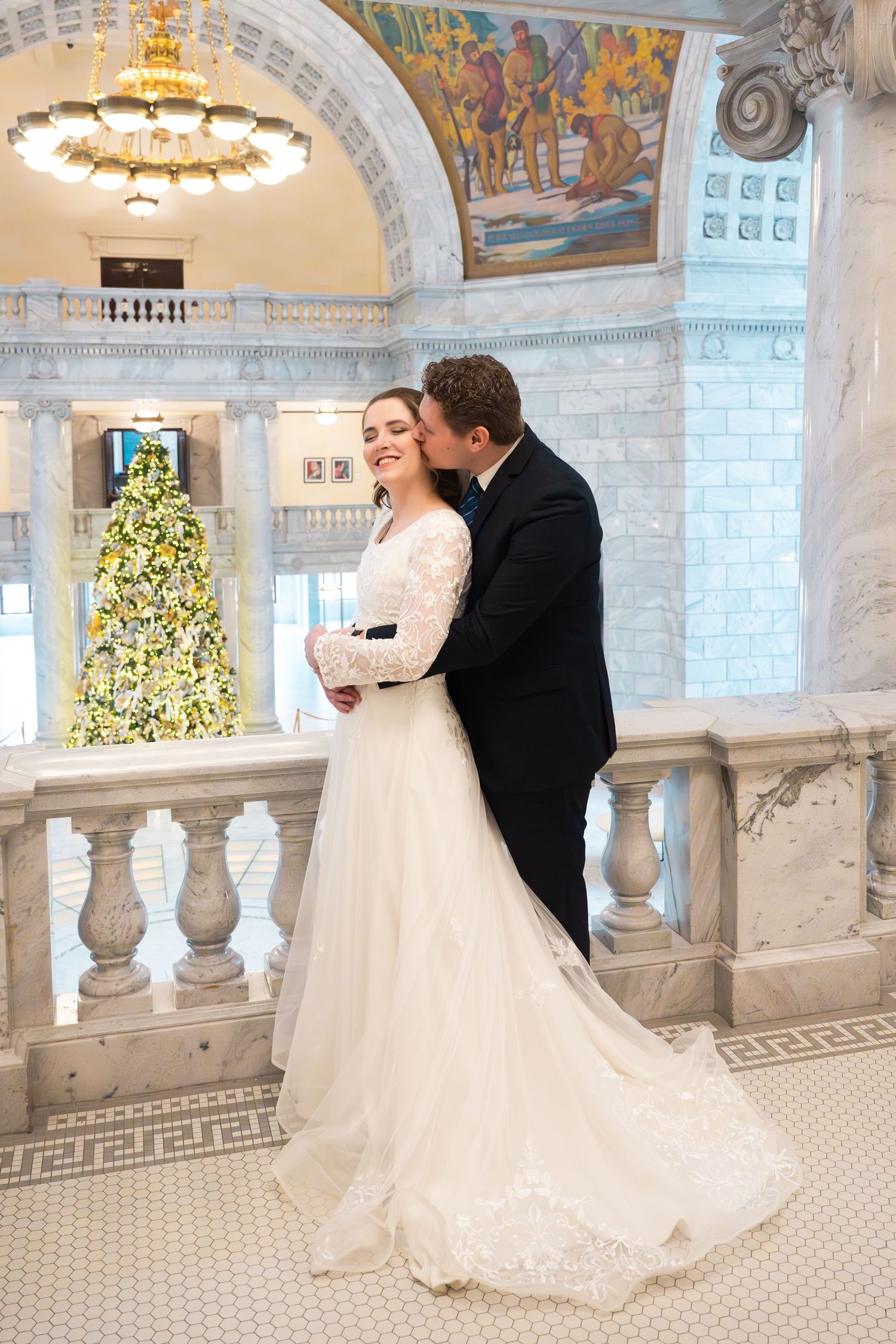 Bride and groom sharing a romantic embrace inside the State Capitol building featuring an elegant architectural setting.