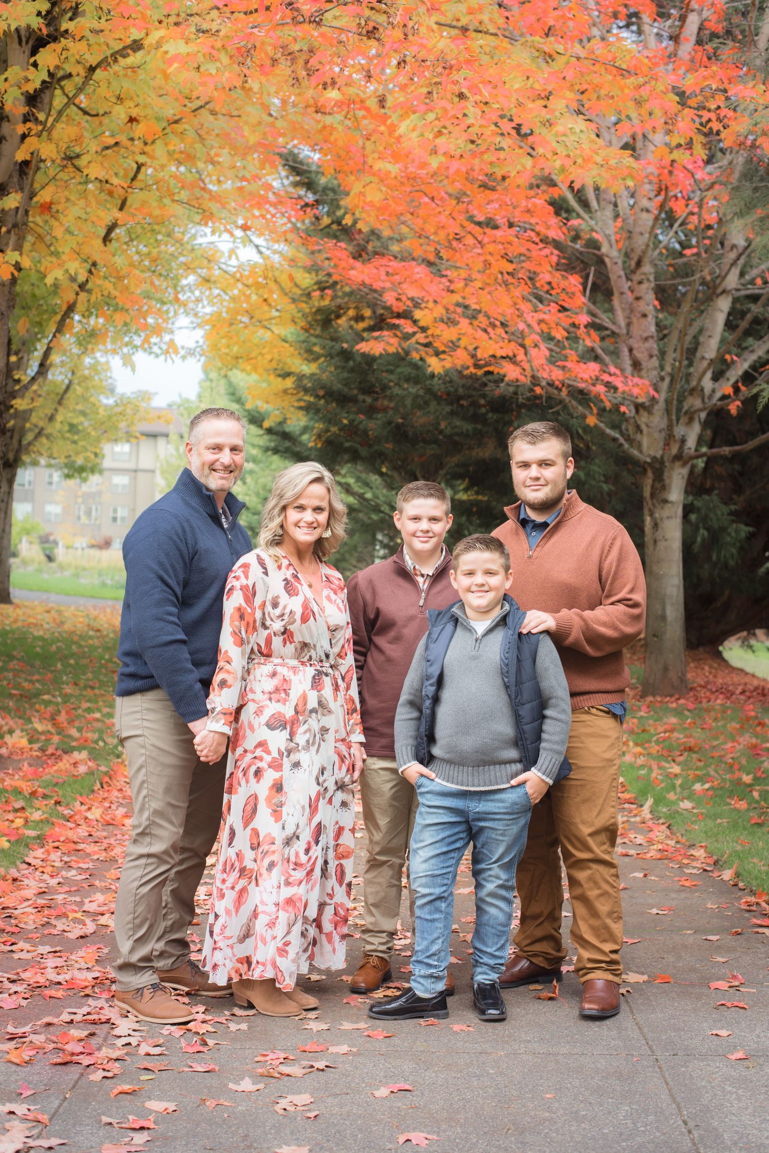 Natural light family portrait surrounded by vibrant autumn leaves in a scenic outdoor setting.