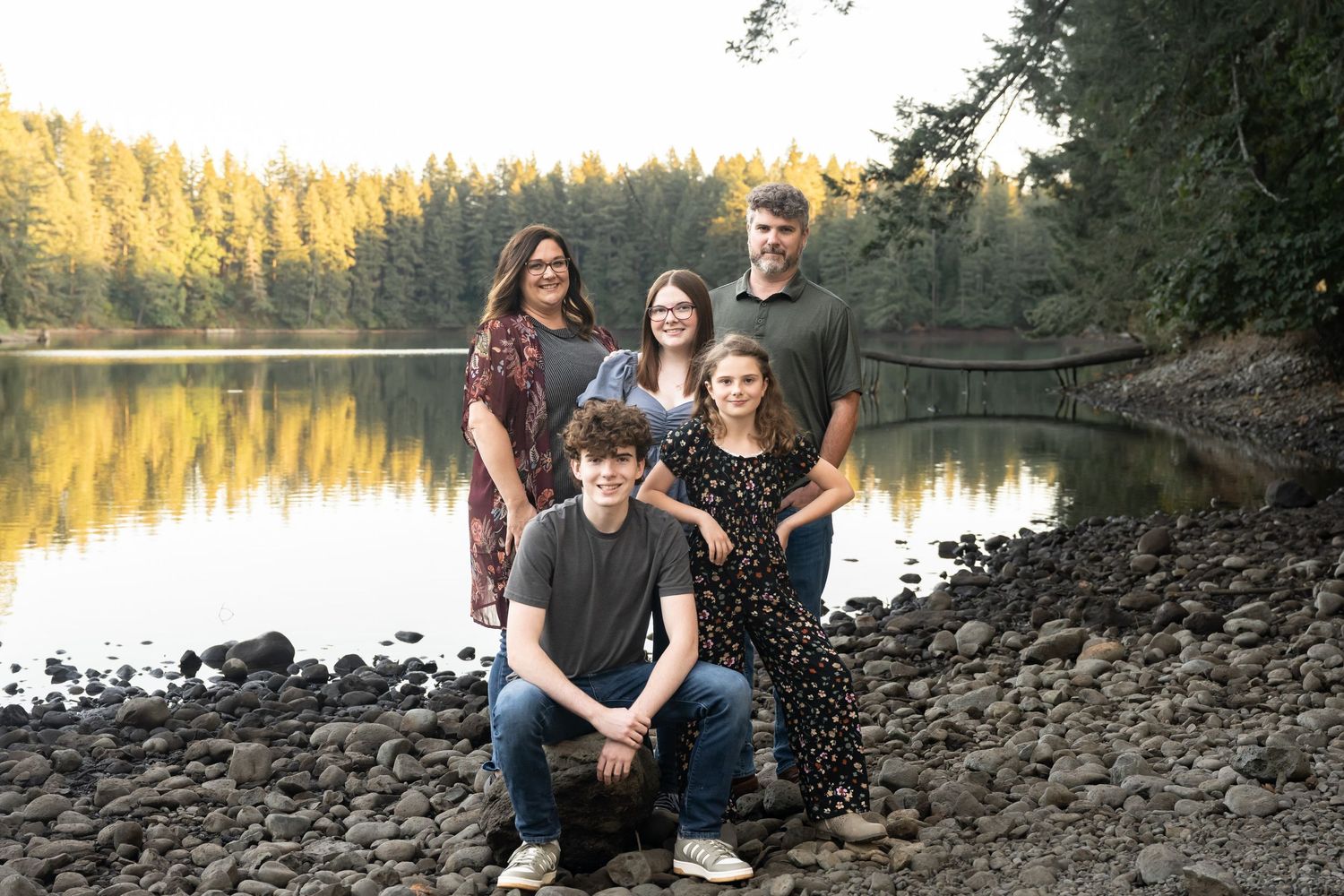 Family portrait by a peaceful mountain lake during a golden hour outdoor family photography session.