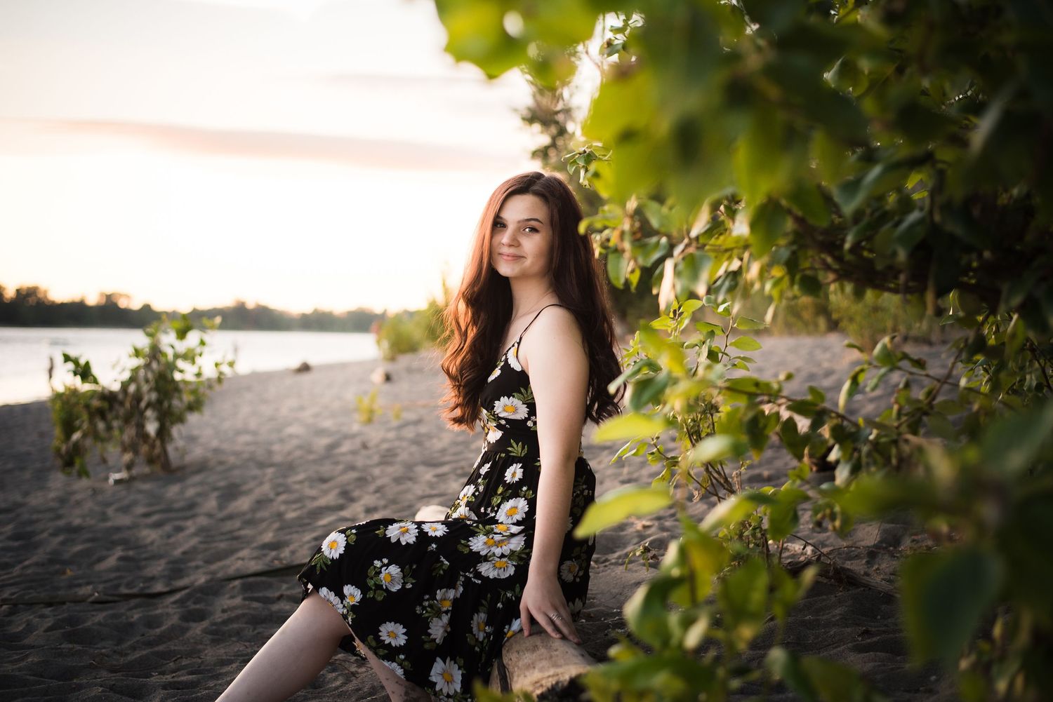 Natural light senior portrait captured beside the water during golden hour.