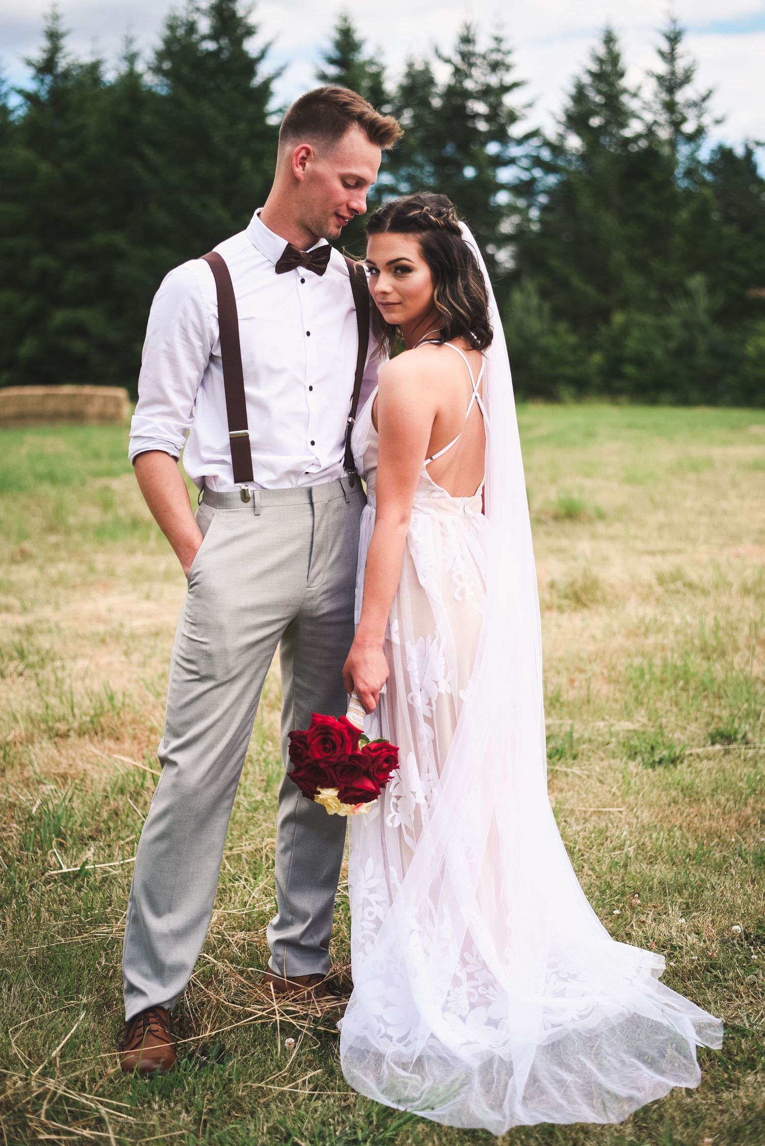 Bride and groom standing together in a scenic field during a natural light wedding portrait session.