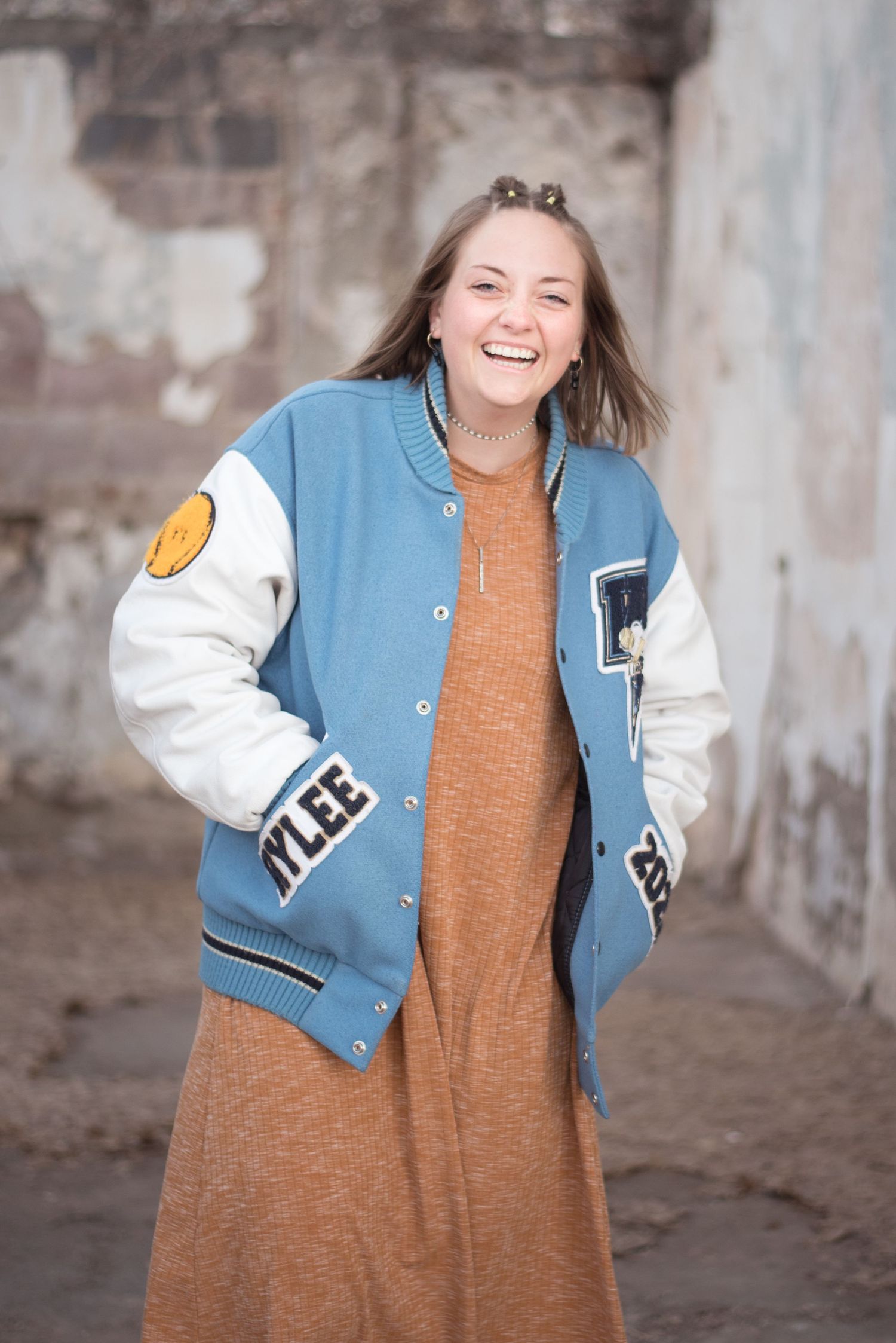 Natural light senior portrait featuring a young woman in a rustic outdoor setting.