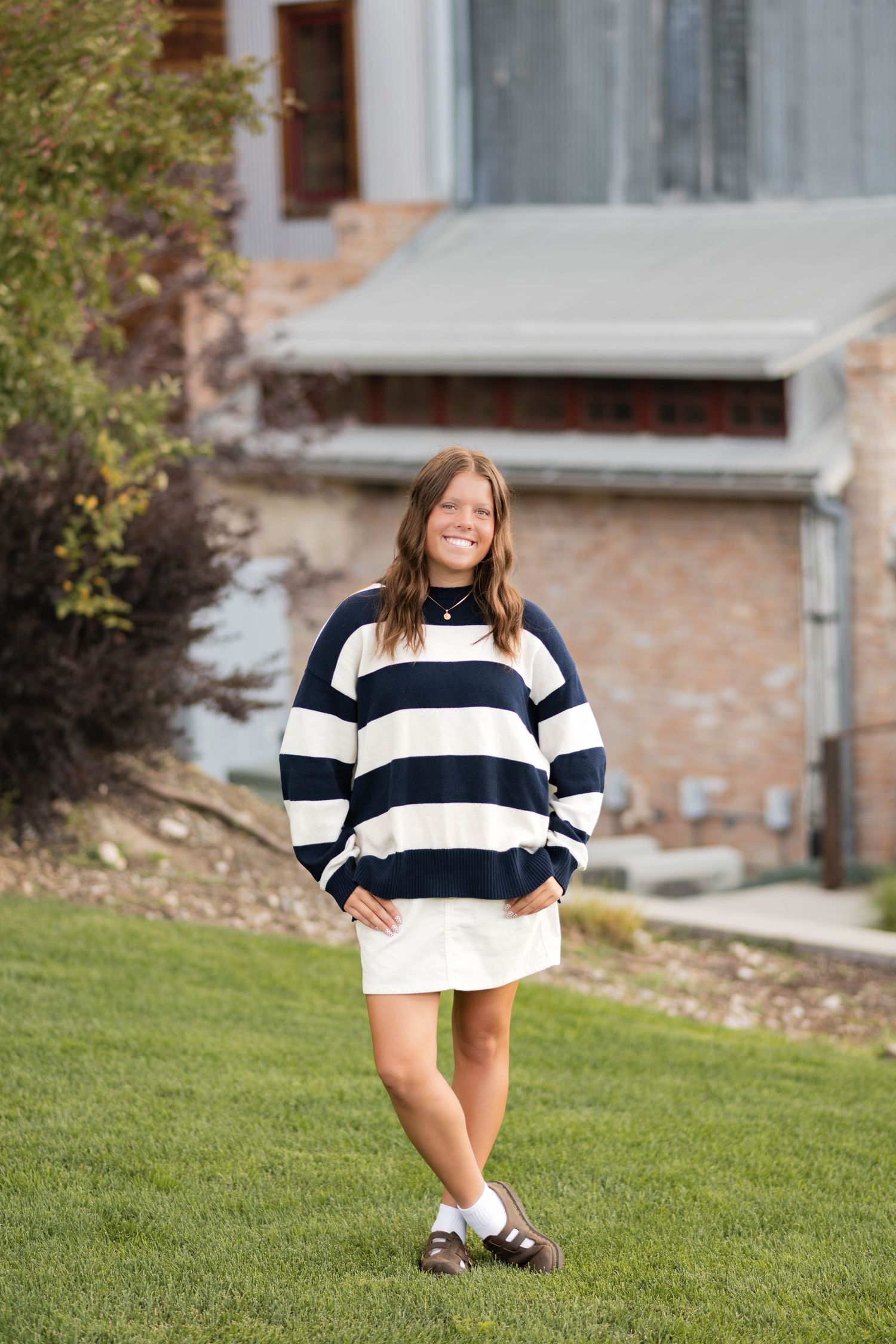High school senior posing in front of a rustic building during a natural outdoor senior photography session in Utah County.
