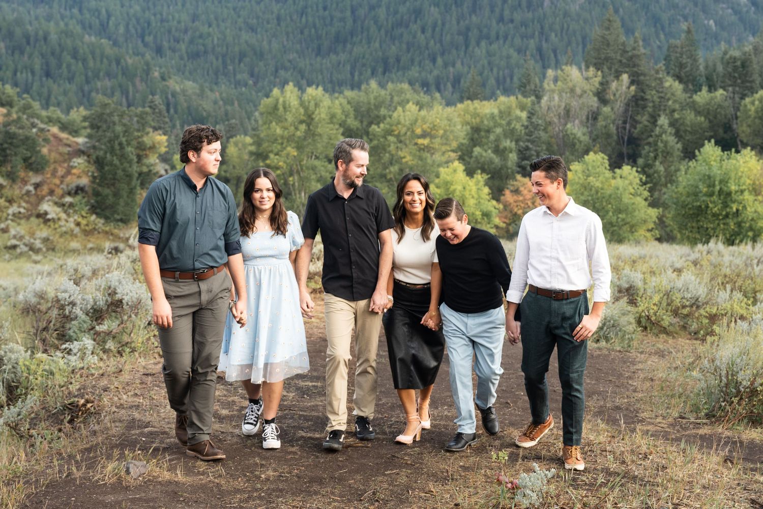 Family walking together through a scenic mountain landscape during an outdoor family photography session.