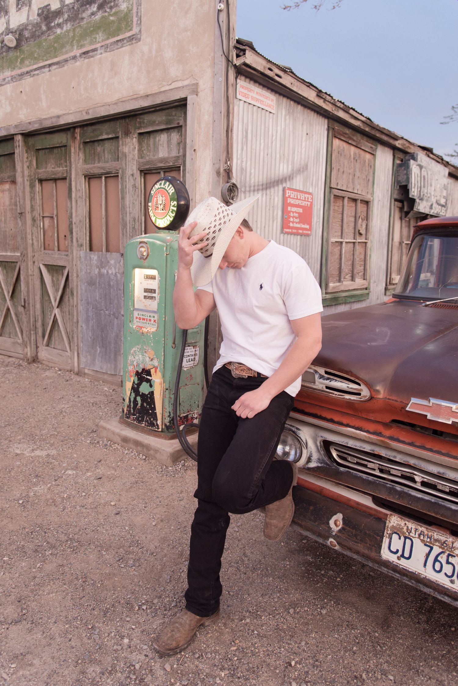 High school senior boy posing beside a classic car in a historic downtown setting during an urban senior photography session in Utah.