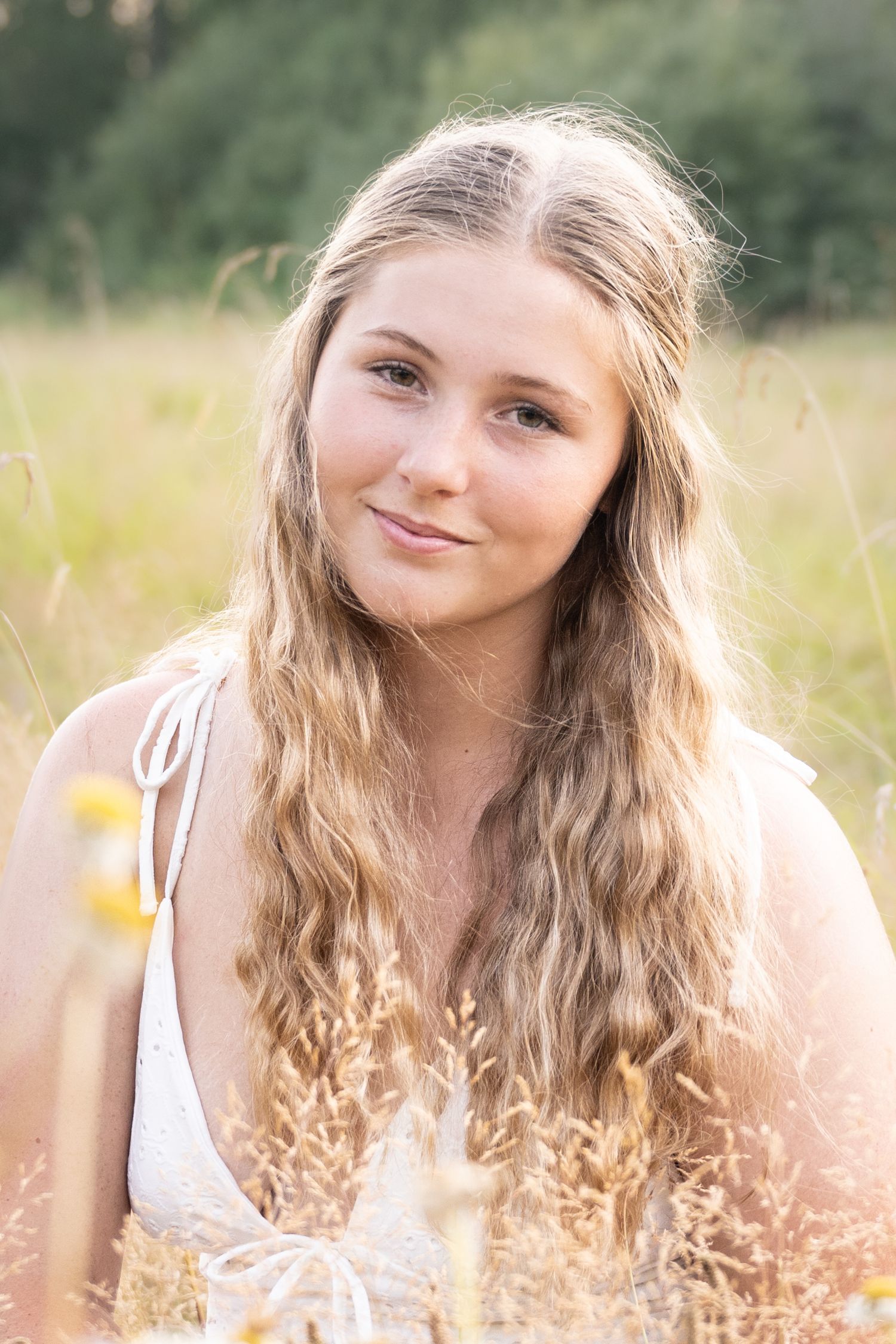 Natural light senior portrait featuring a young woman surrounded by tall grass.