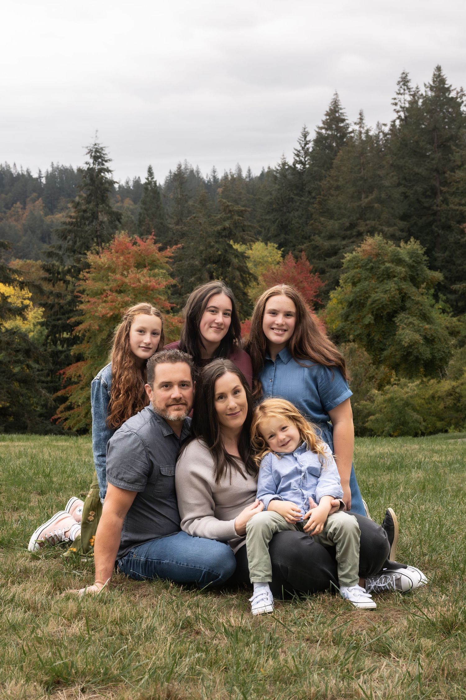 Smiling family sitting together outdoors during a natural lifestyle family photography session.