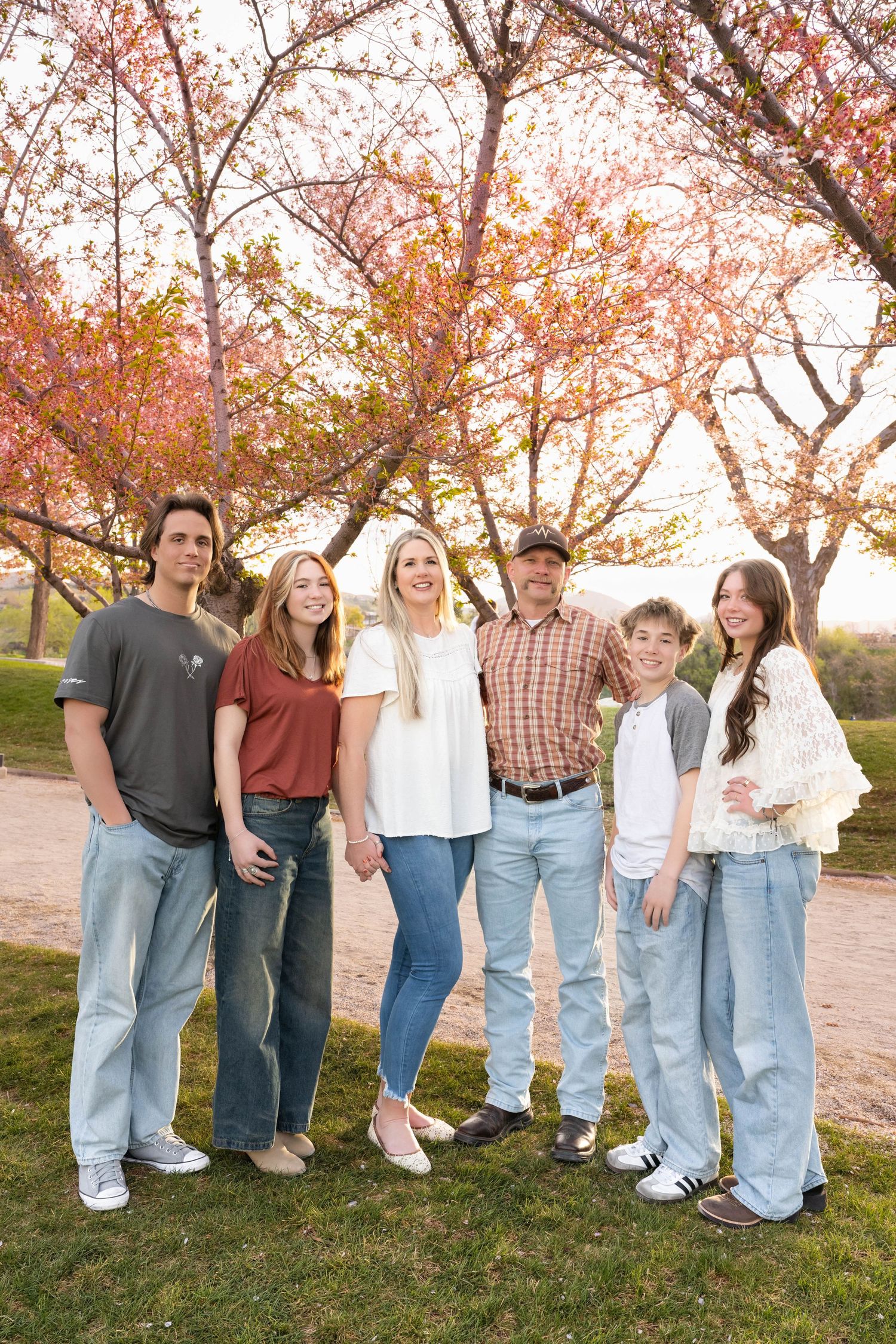 Family standing together beneath colorful spring trees during an outdoor family photography session.