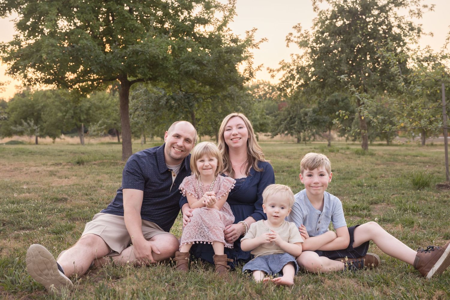Natural light family portrait featuring parents and children in a relaxed outdoor setting.