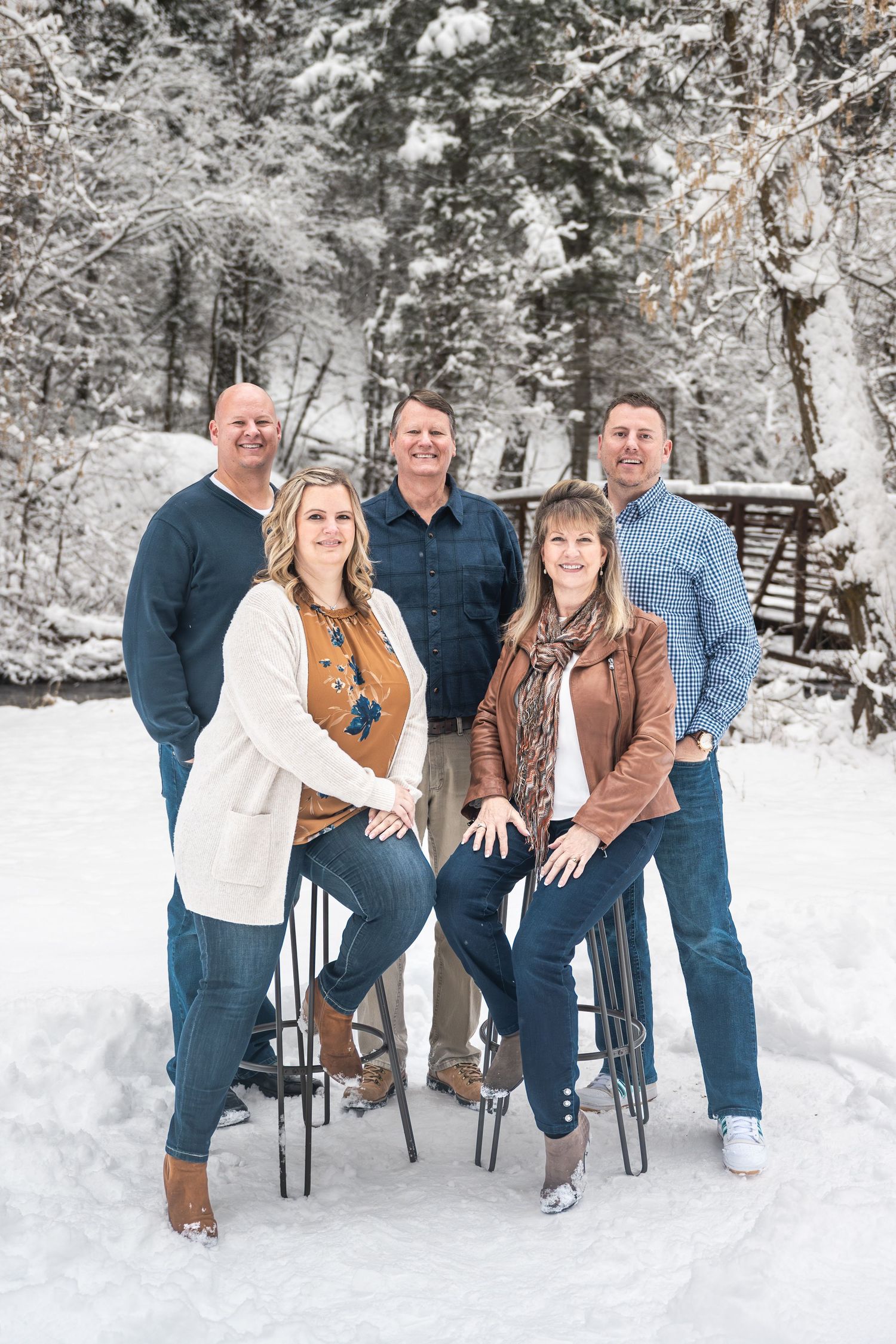 Family of five adults smiling together in a snowy winter landscape during an outdoor family photography session in Utah.