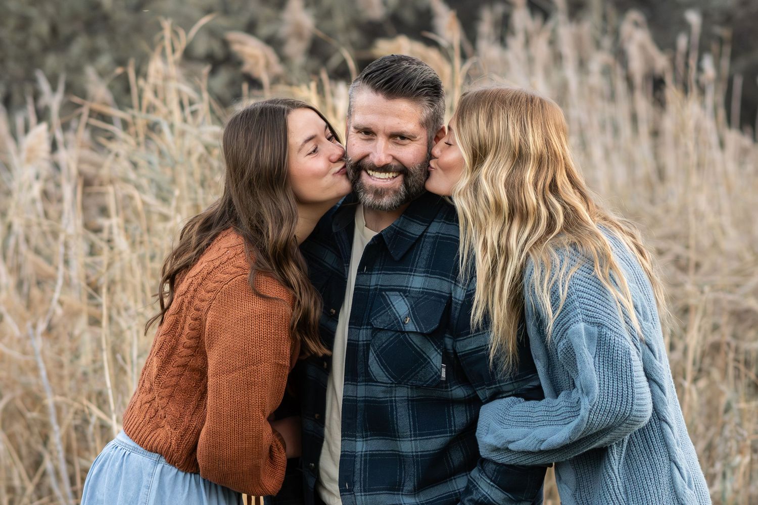 Dad sharing a joyful moment with his daughters during a natural outdoor family photography session.