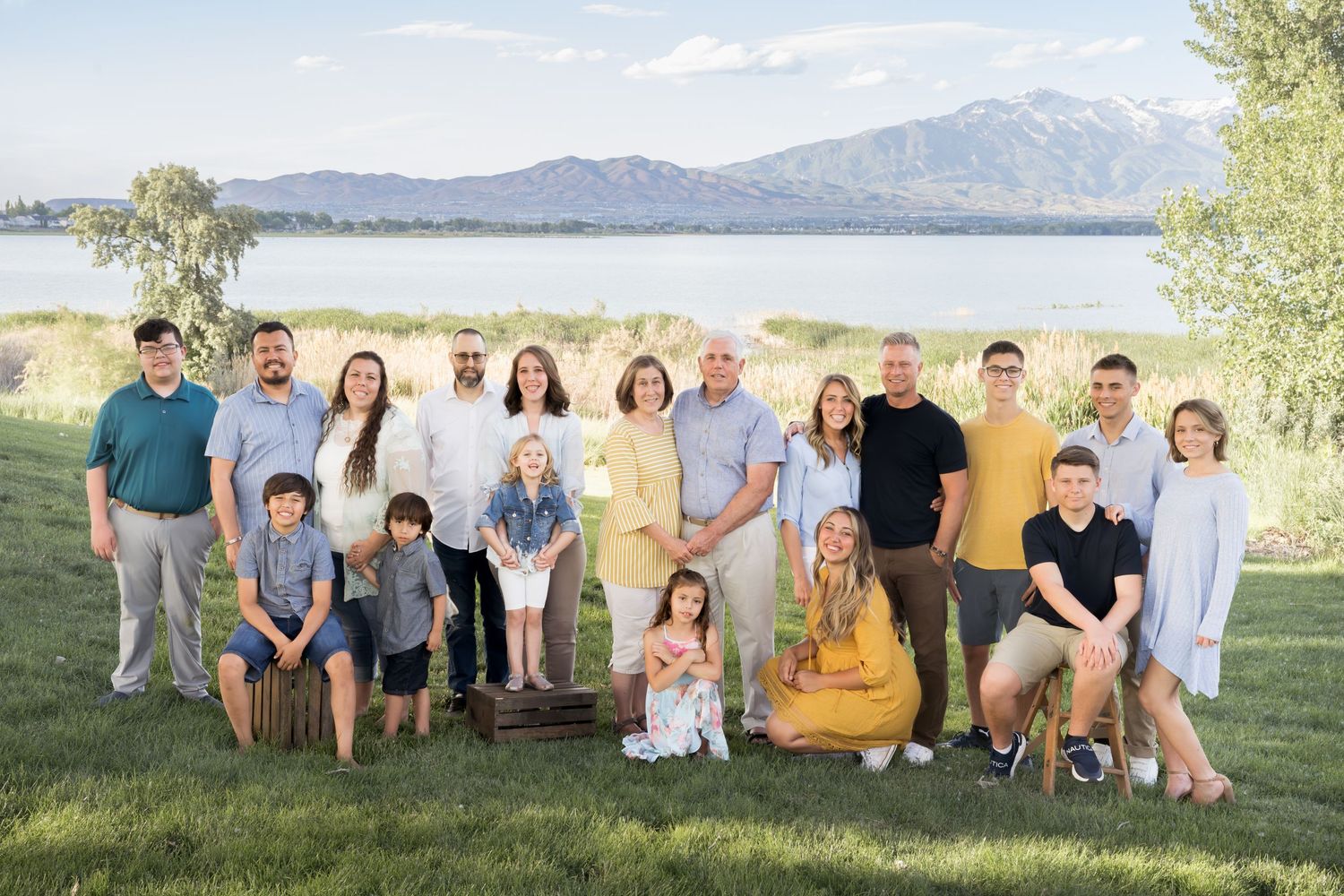 Extended family portrait gathered outdoors with beautiful lake and mountain views in the background.