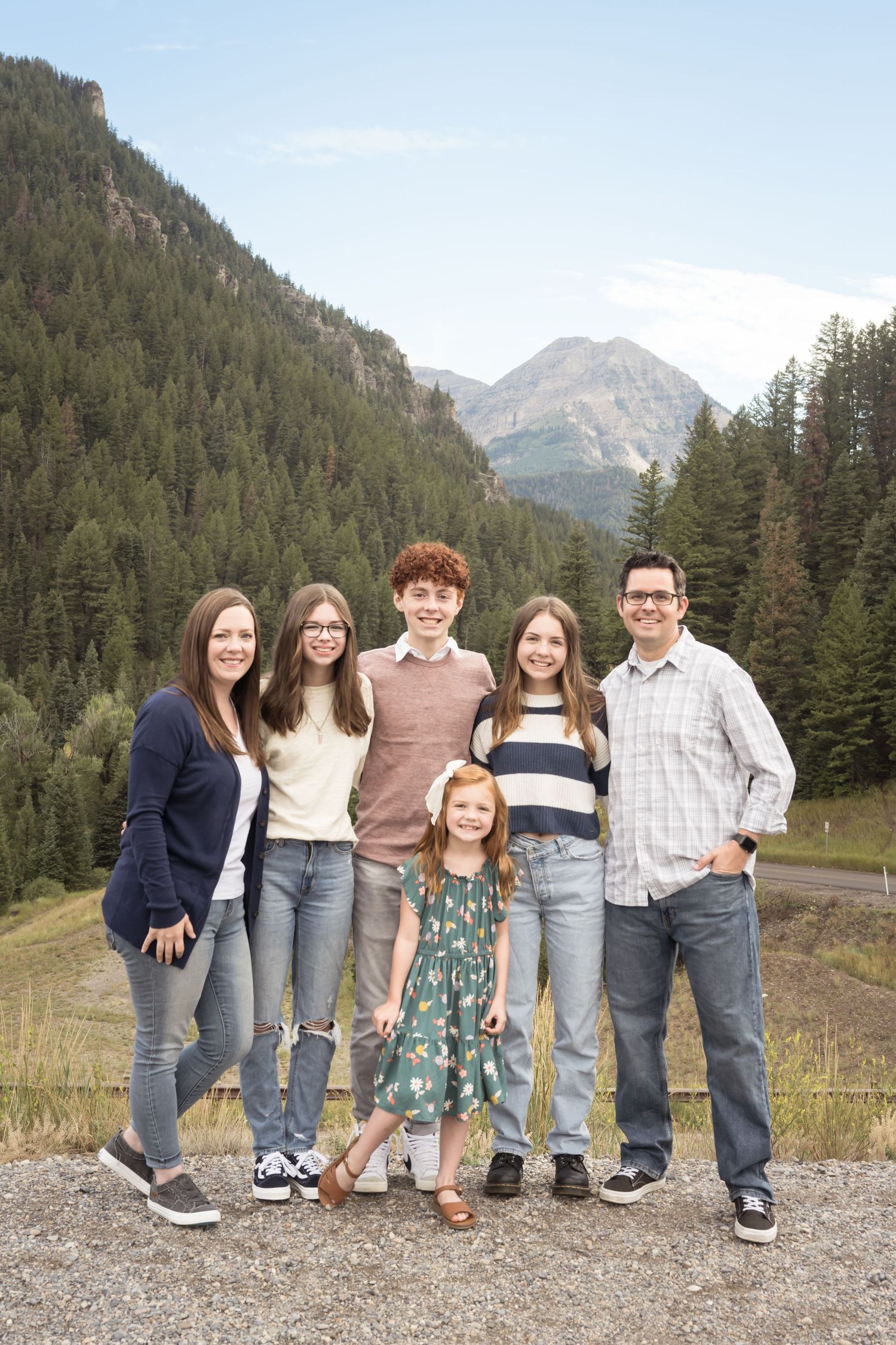Family of five posing together with beautiful mountain views during an outdoor photography session at Tibble Fork, UT.