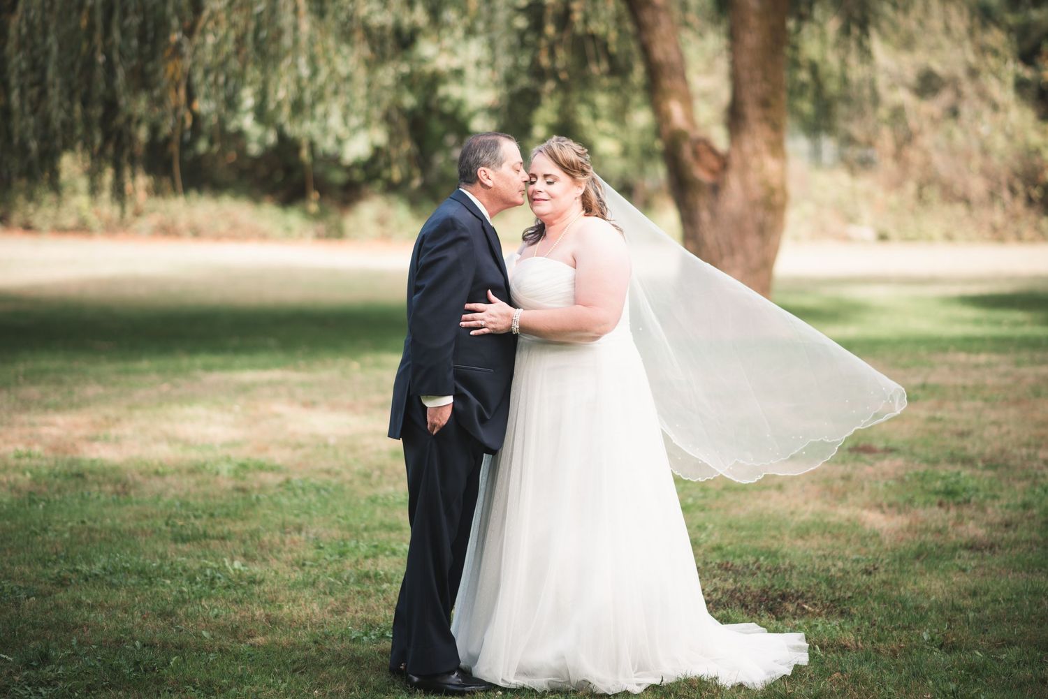 Romantic wedding portrait of newlyweds sharing a quiet moment beneath the trees.