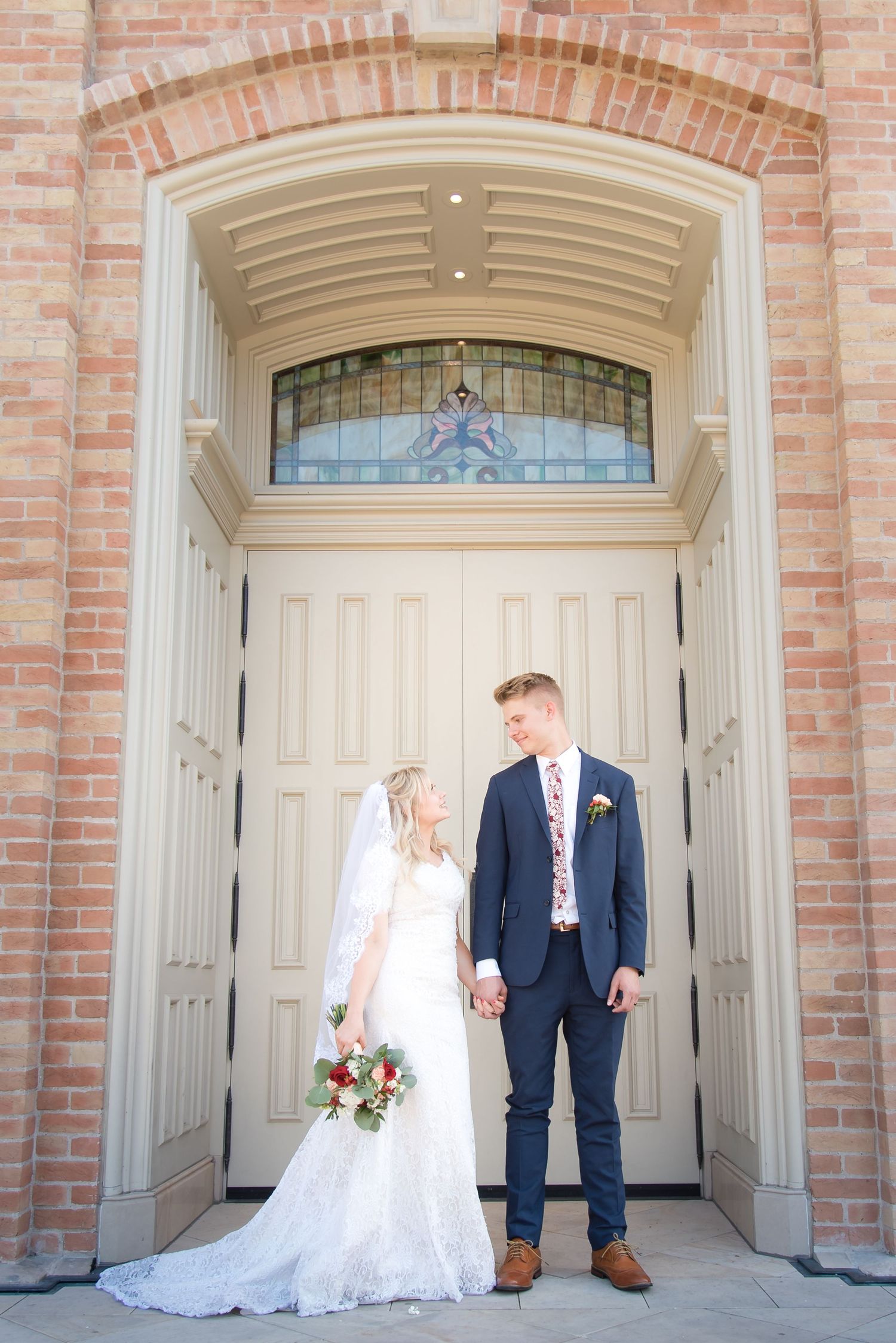 Bride and groom standing together outside the wedding venue during romantic wedding portraits.