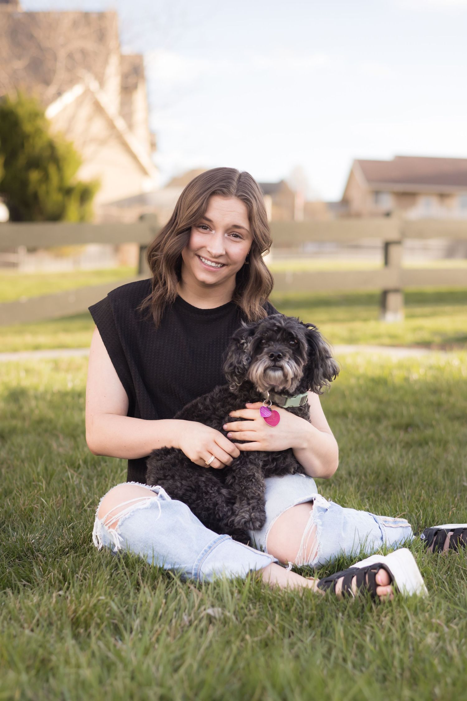High school senior girl sitting on the grass with her dog during a relaxed outdoor senior portrait session in Utah.