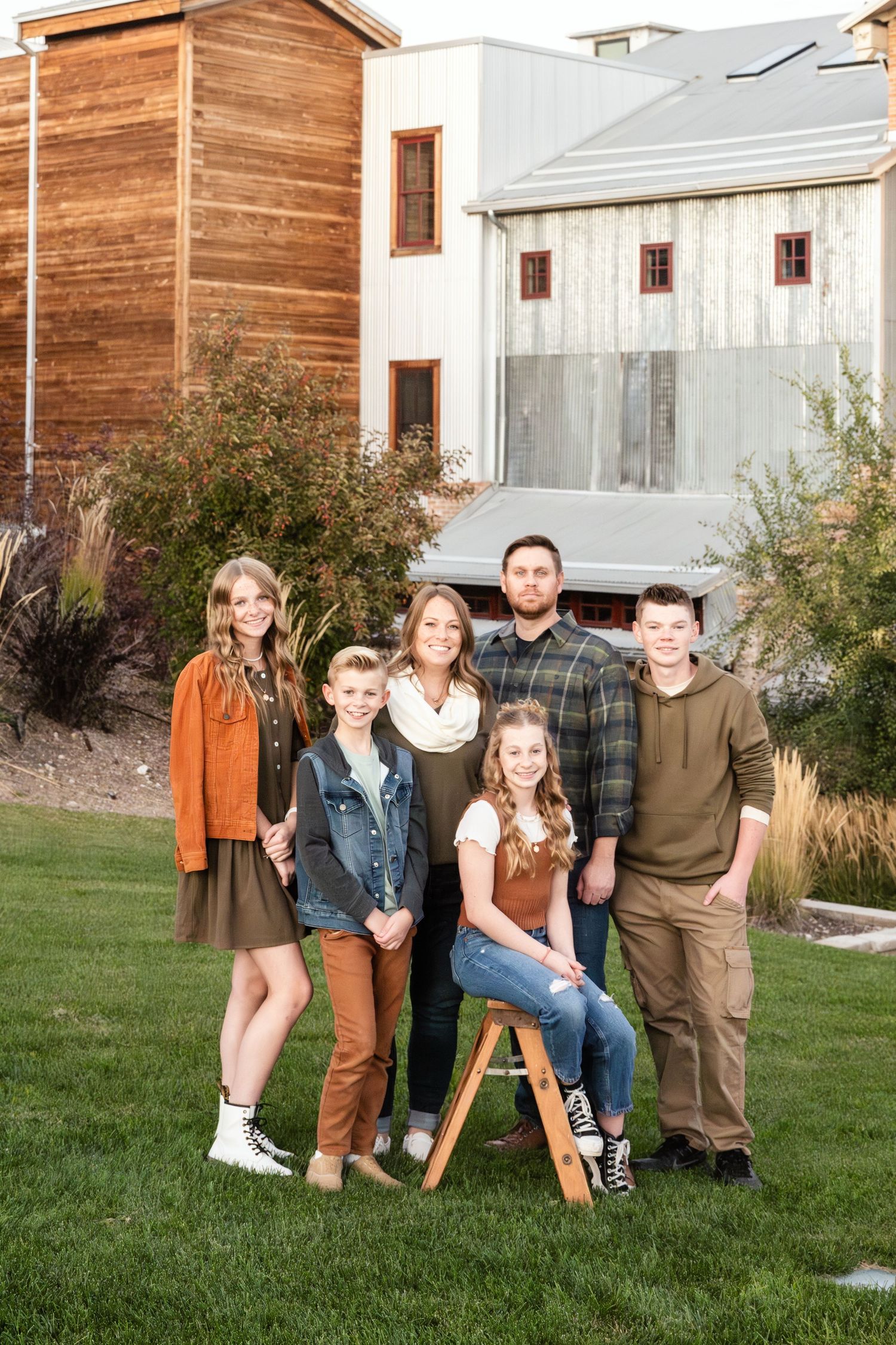Family of five smiling together outdoors in front of a modern building during a natural light family photography session in Utah.