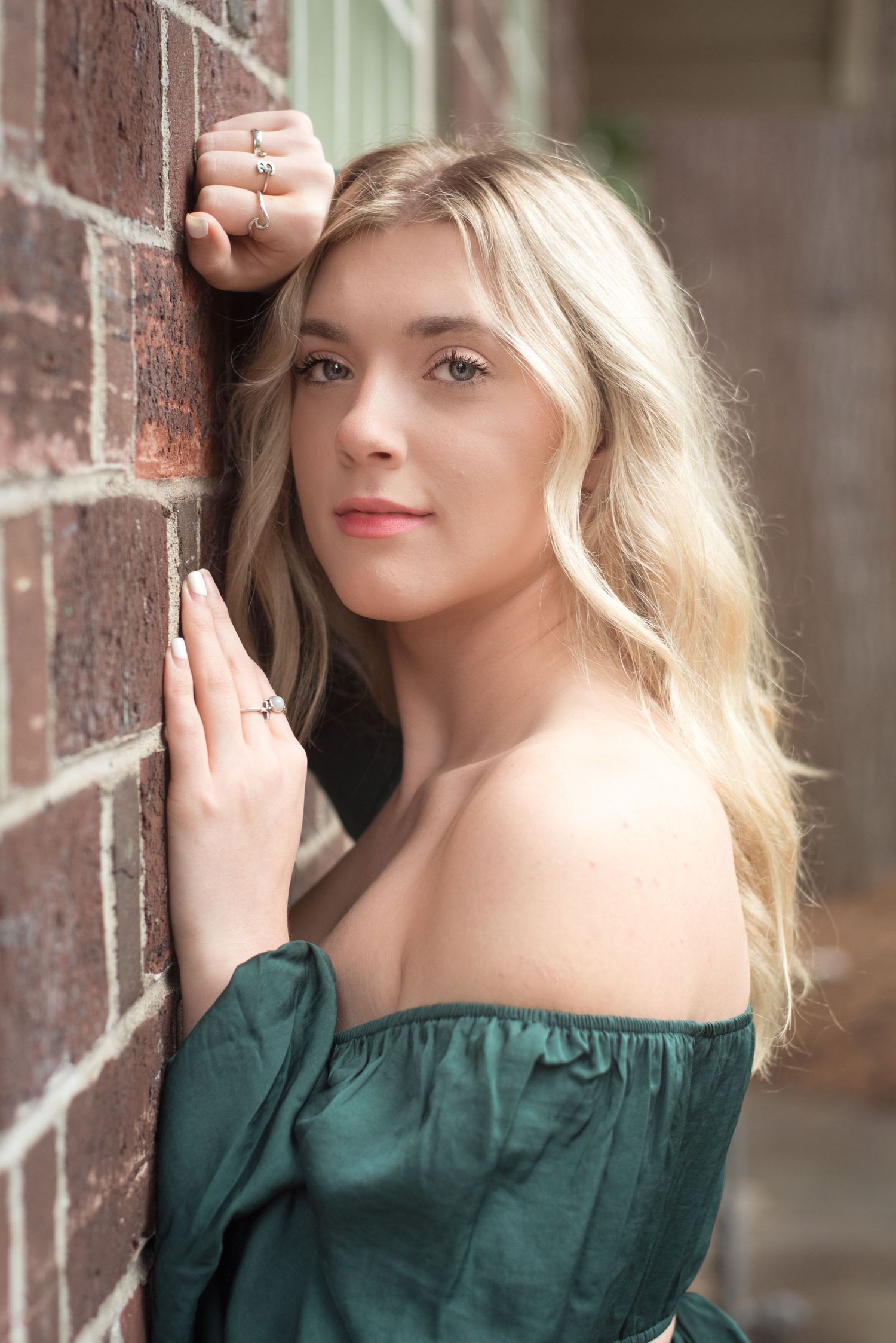 Beautiful senior portrait featuring a young woman against a rustic brick backdrop.
