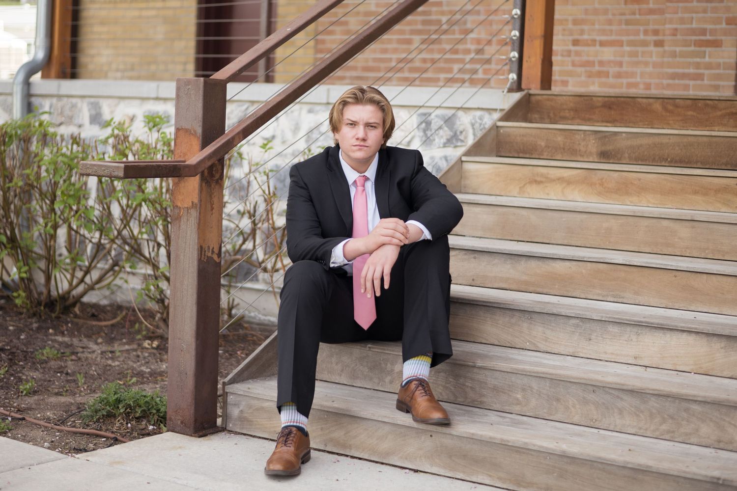 High school senior boy portrait sitting on outdoor steps during a relaxed senior photography session in Utah County.