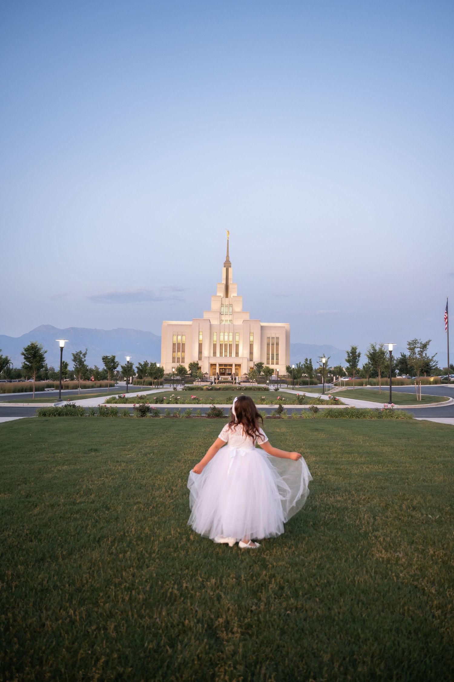 Young Child standing in front of the Saratoga Springs Temple at sunset during a Baptism photography session.