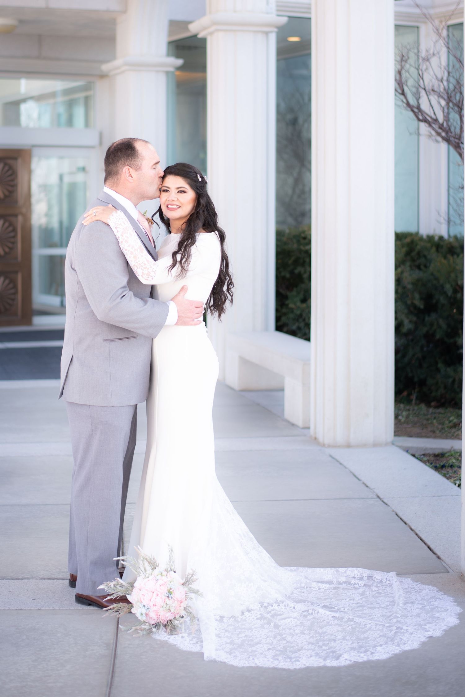 Bride and groom sharing an elegant wedding portrait beneath the temple columns after their ceremony.