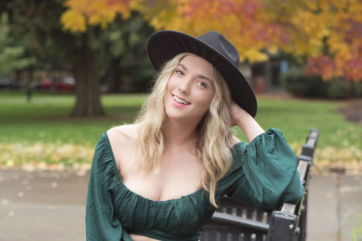 Natural light senior portrait featuring a young woman surrounded by colorful autumn leaves.
