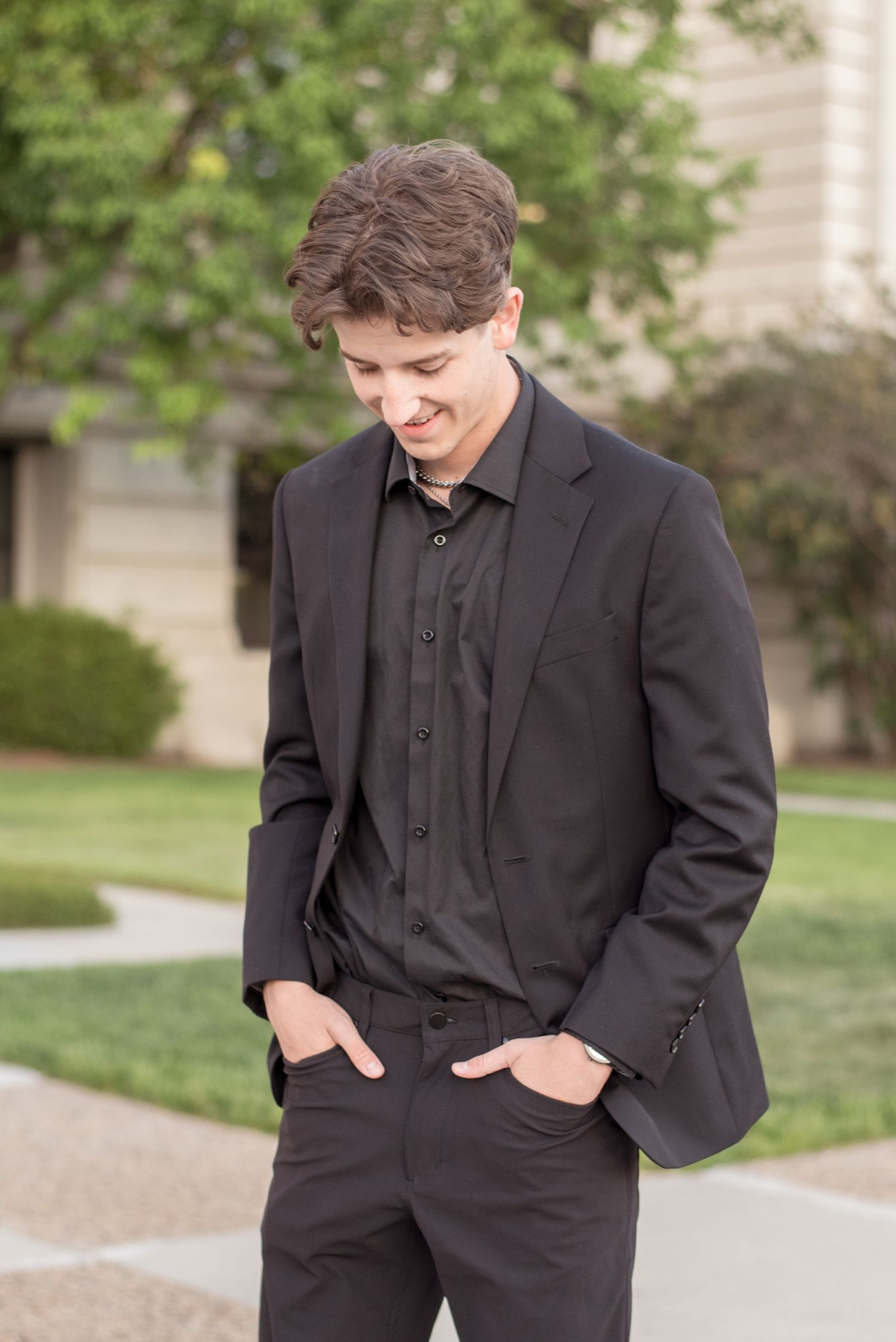 High school senior boy wearing a black suit during an elegant outdoor senior portrait session with natural light in Utah.