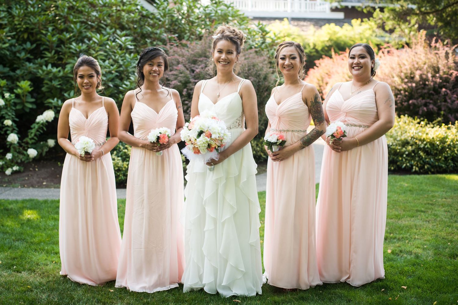 Natural light bridal party portrait featuring the bride and bridesmaids holding their bouquets.