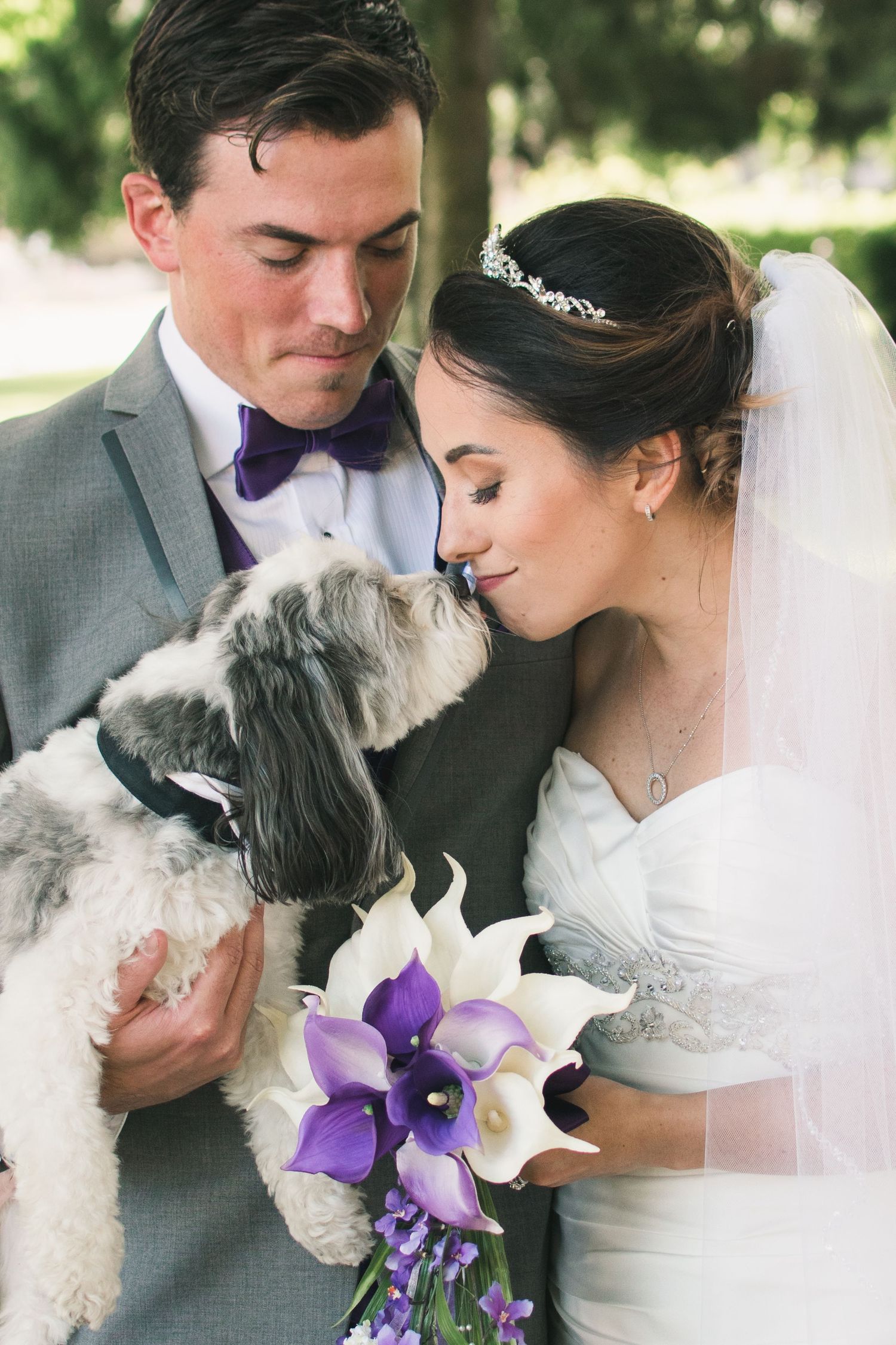 Romantic wedding portrait featuring newlyweds embracing with their dog on their wedding day.