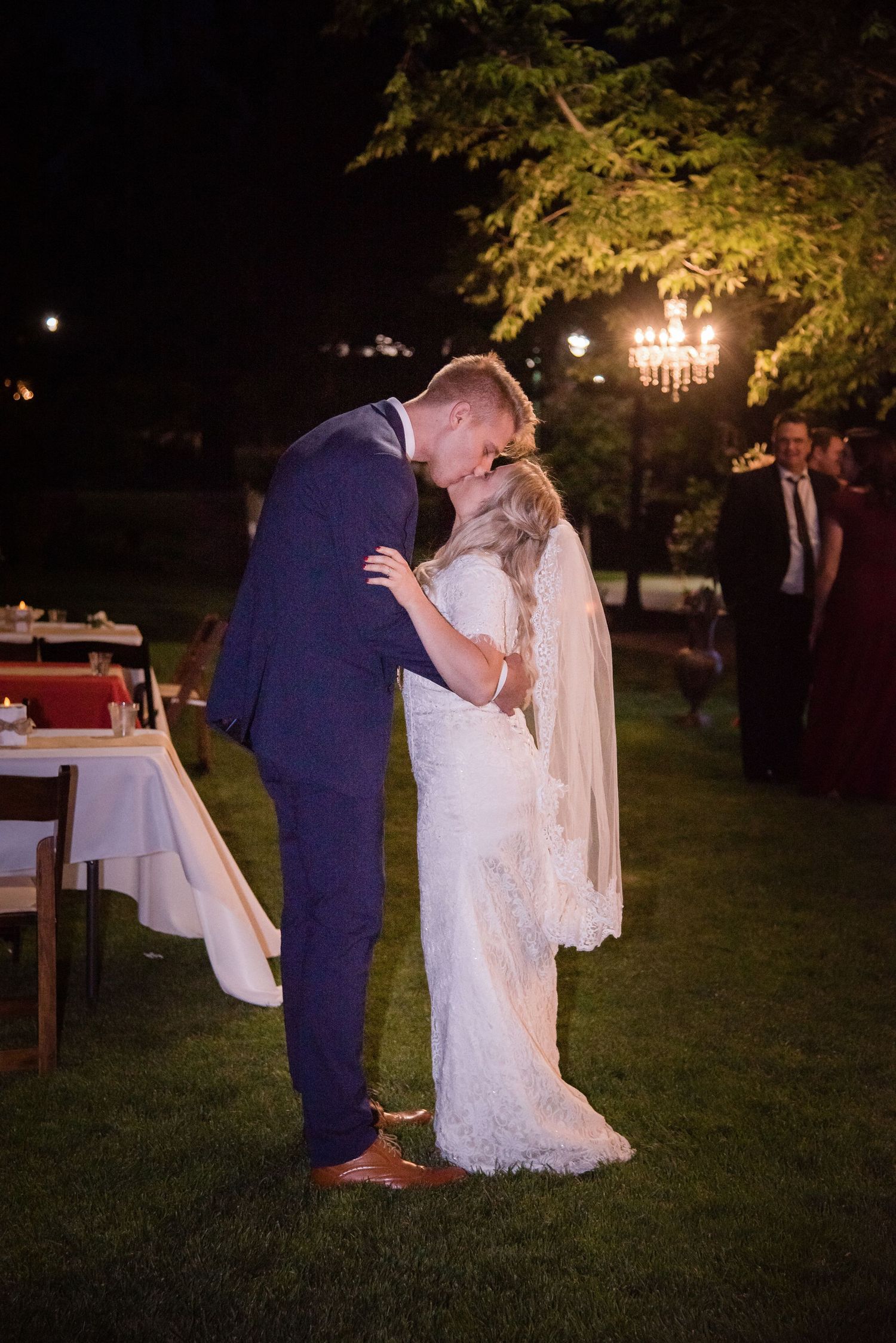 Bride and groom sharing a romantic nighttime portrait illuminated by soft ambient light.