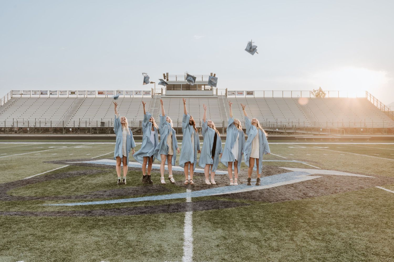 Graduating seniors tossing their caps in the air during a graduation photography session.