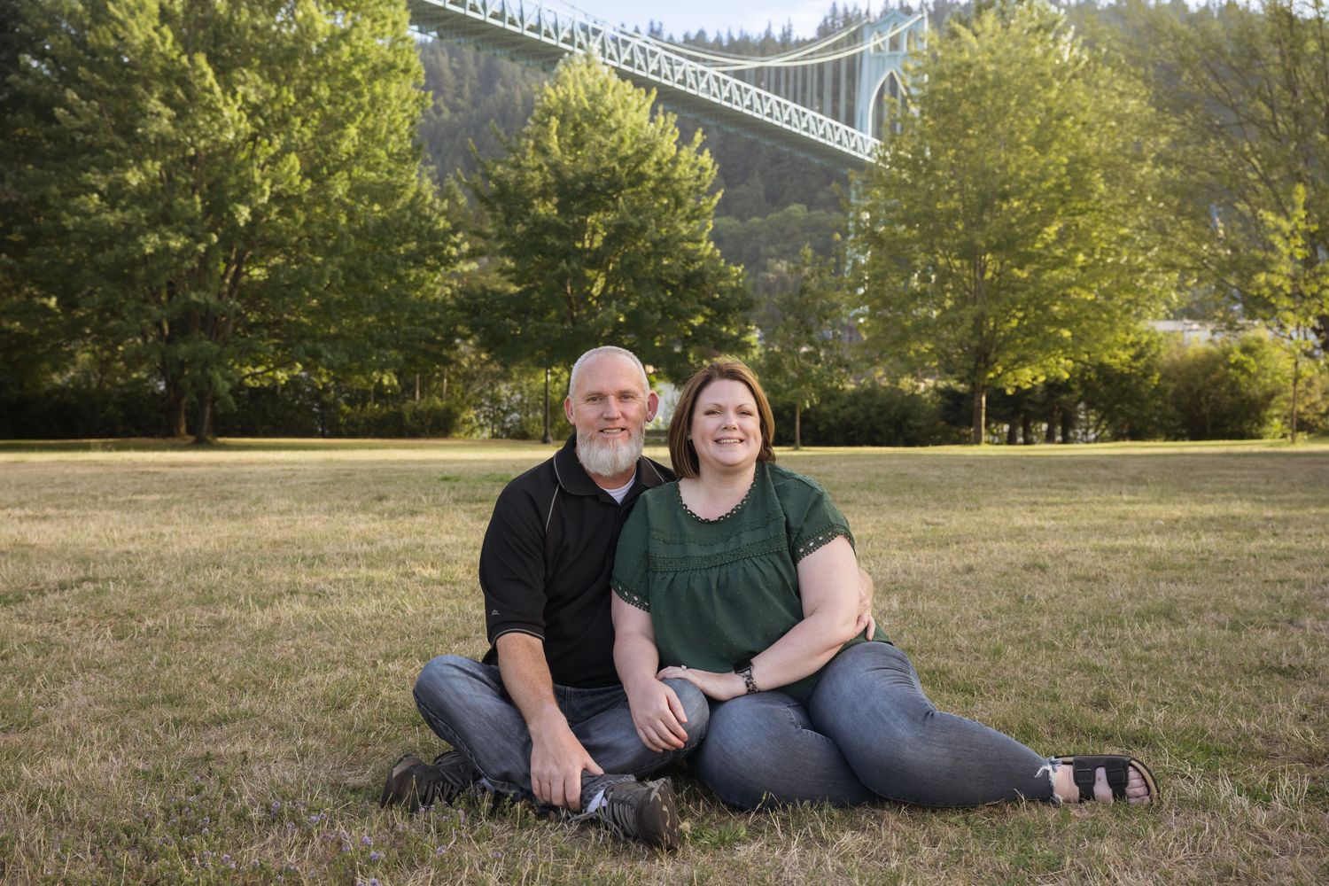Couple sitting together in a scenic park during a relaxed photography session.