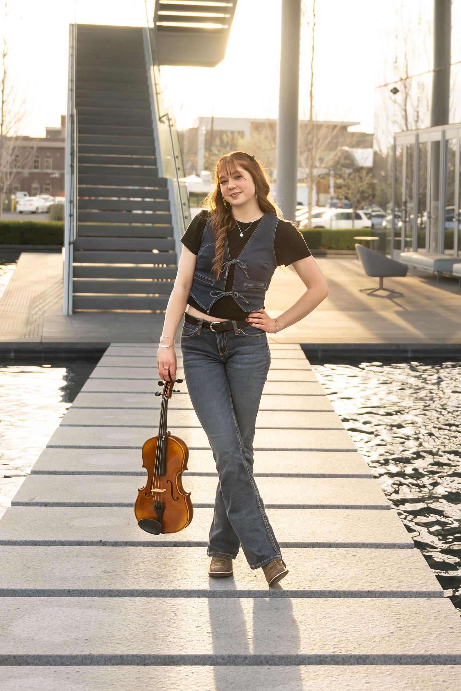 High school senior girl posing beside a city waterfront during golden hour in an urban senior photography session.