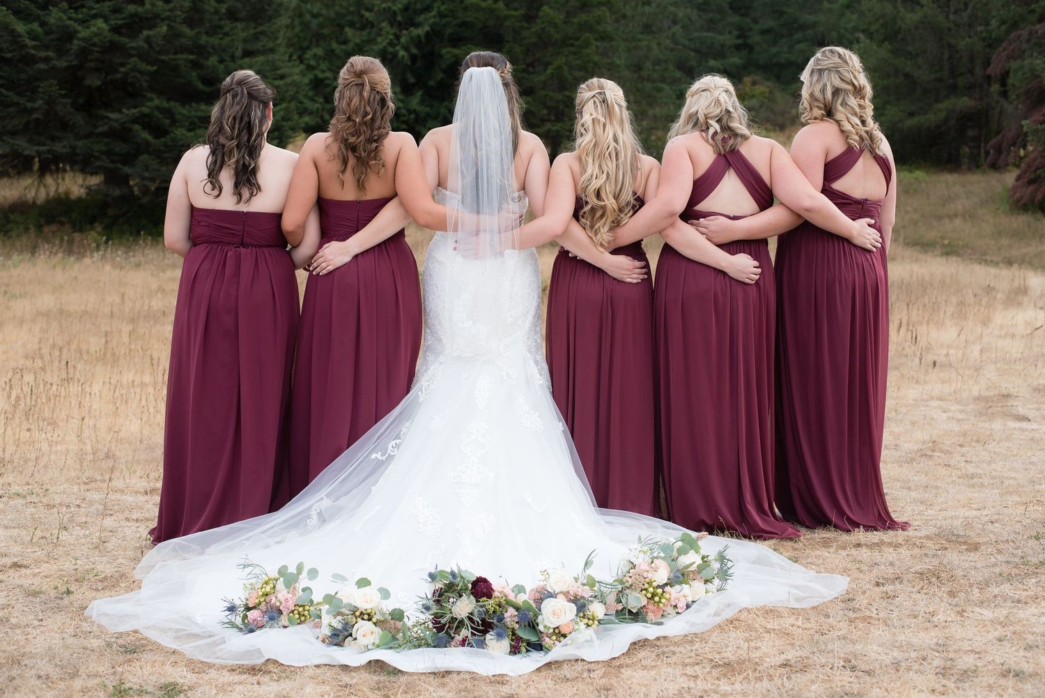 Back view of the bride and bridesmaids celebrating together in matching burgundy dresses.