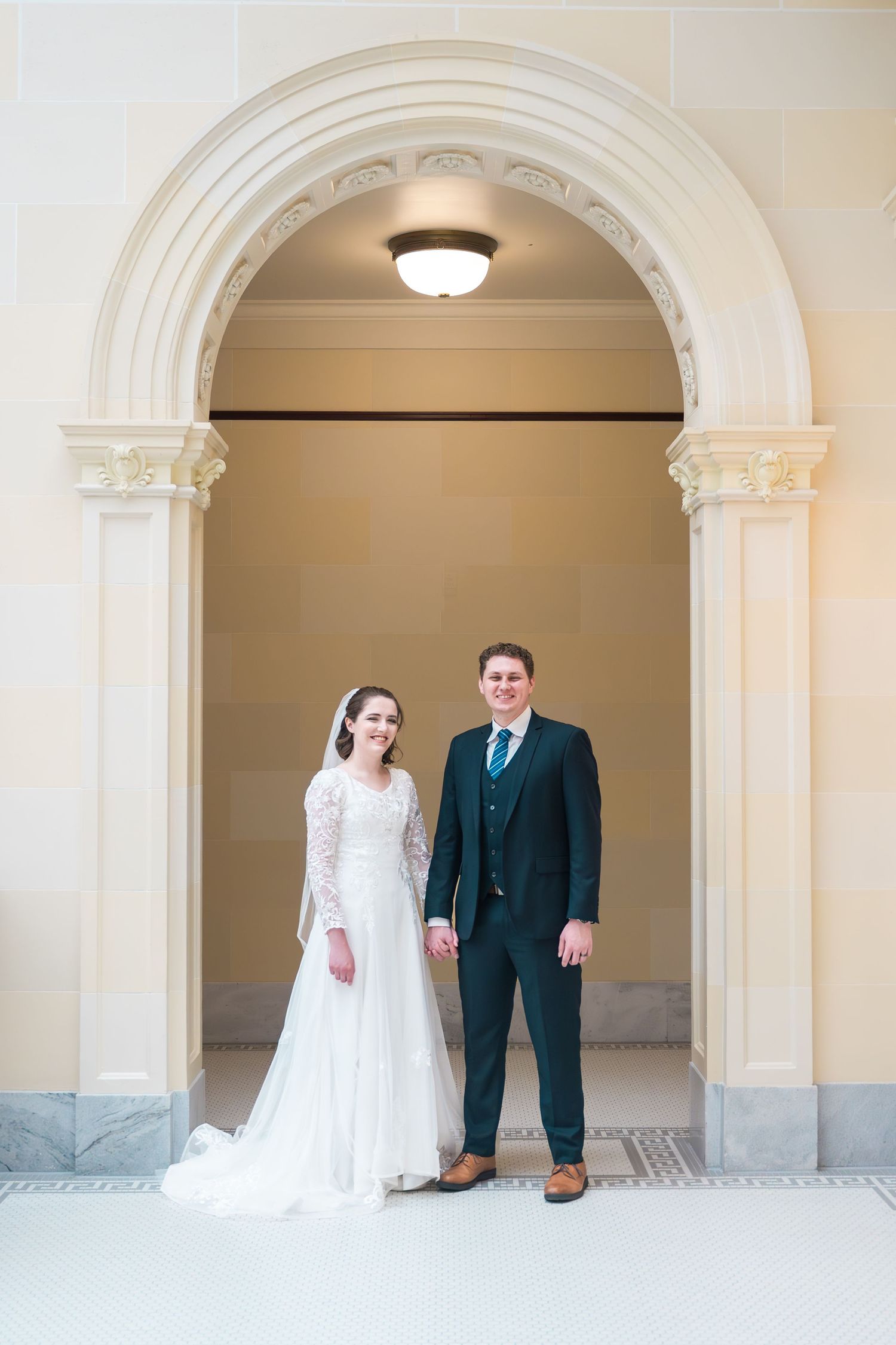 Bride and groom standing beneath an elegant archway during a timeless Utah wedding photography session.