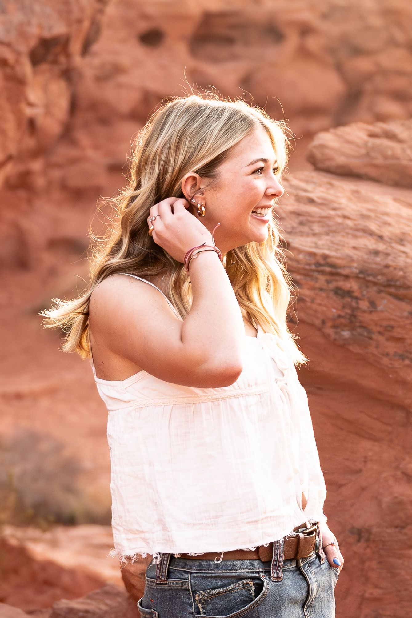 High school senior portrait in front of Utah red rock cliffs during sunrise.