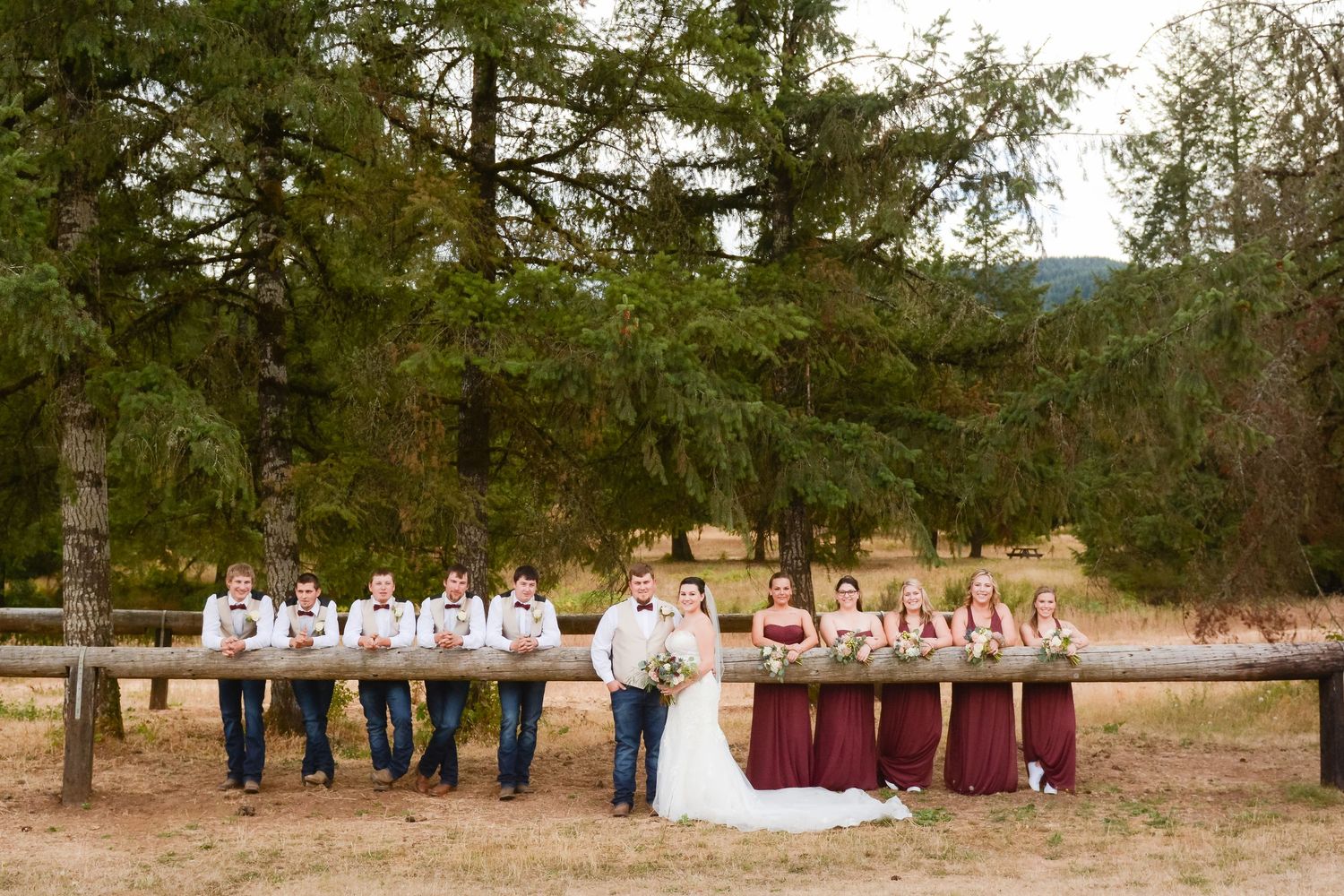 Bride, groom, bridesmaids, and groomsmen gathered for a formal outdoor wedding party portrait.