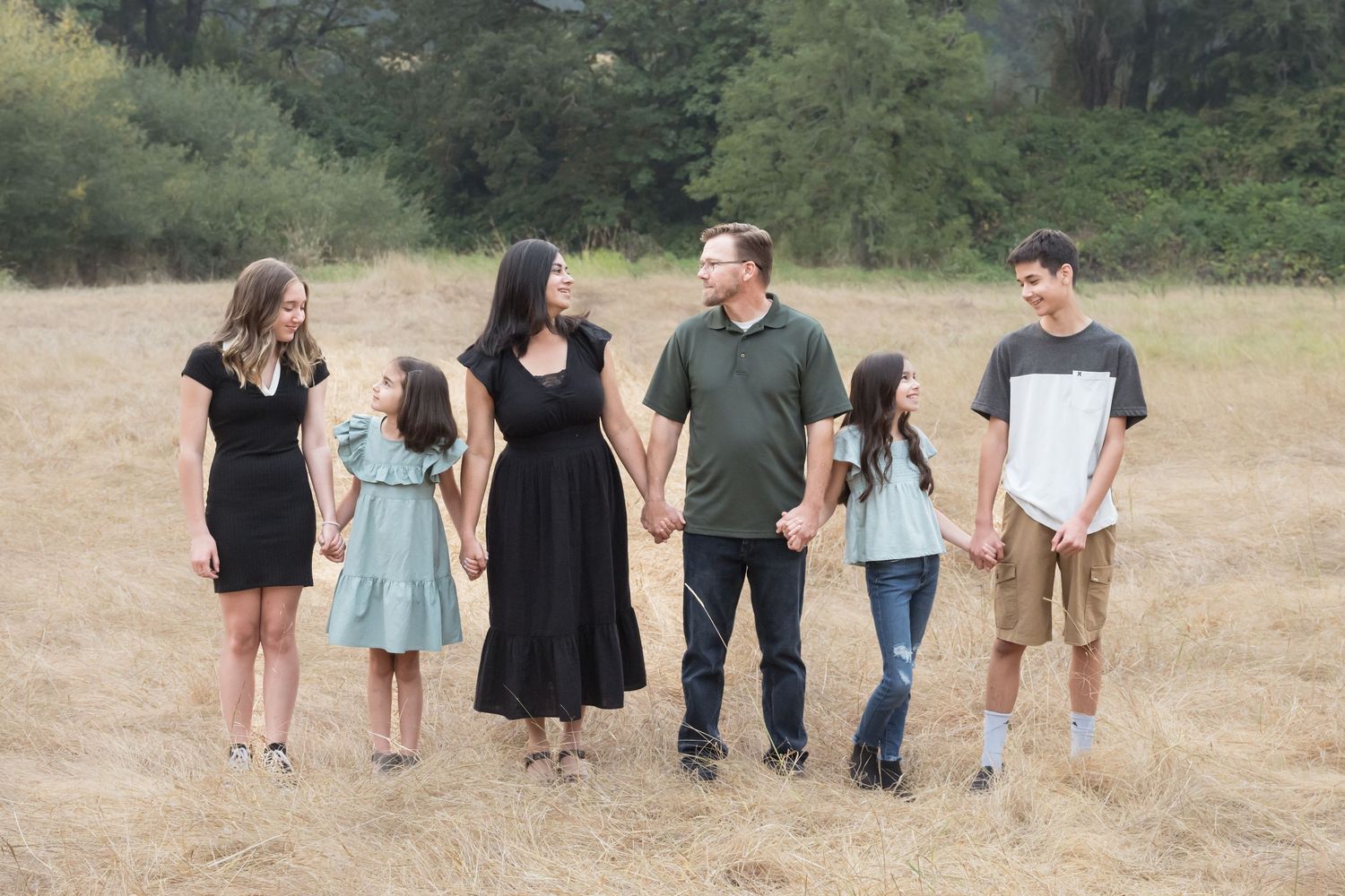 Family standing together in an open field during a relaxed outdoor family photography session.