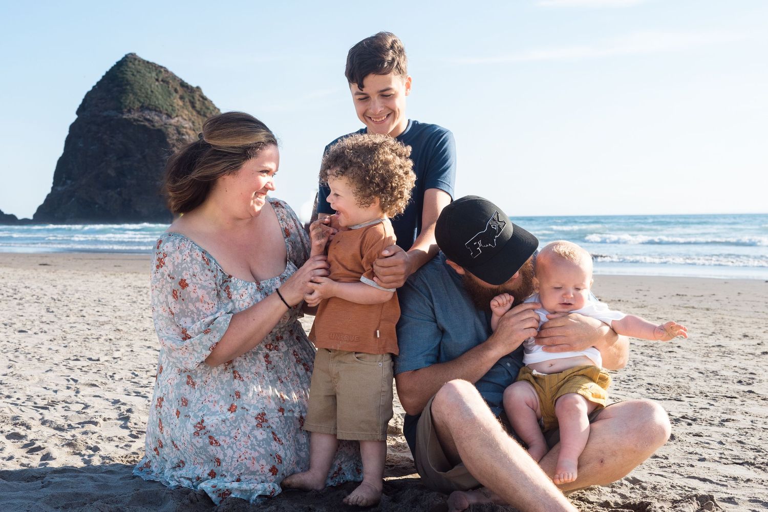 Family laughing together on the beach during a candid coastal family photography session.