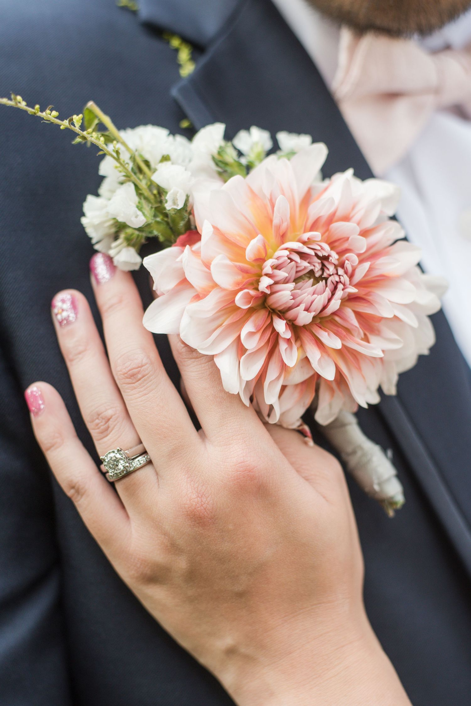 Close-up of the bride's wedding ring and boutonnière during a wedding photography session.