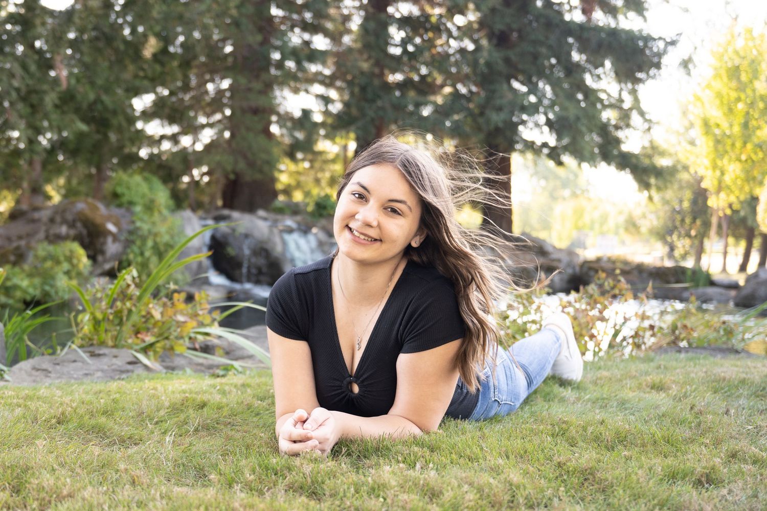 Natural light senior portrait featuring a young woman relaxing in a beautiful park setting.