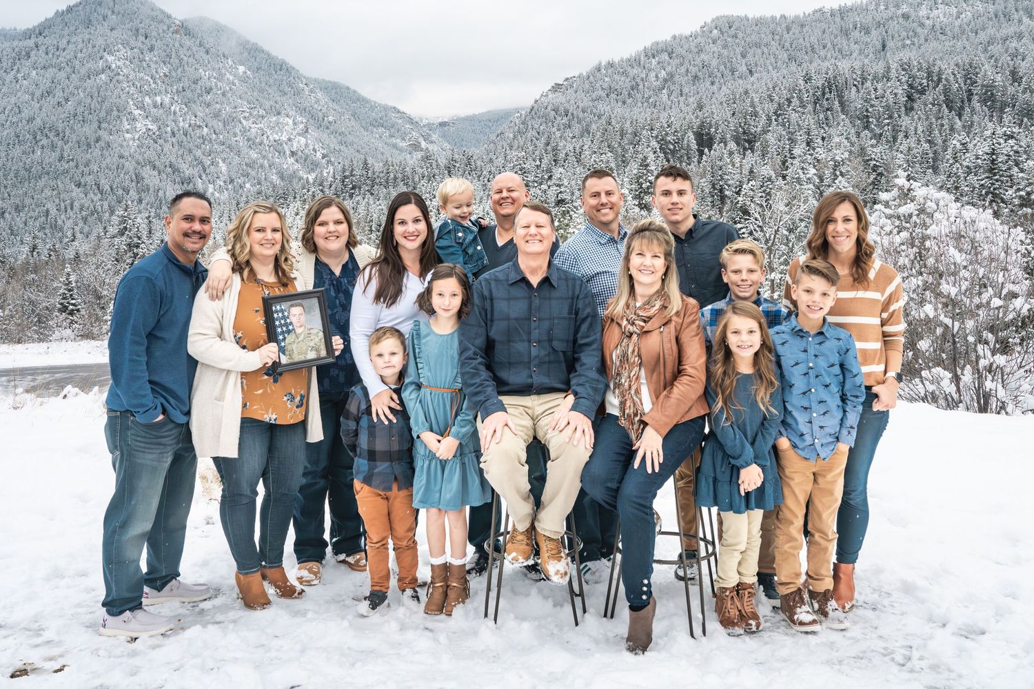 Large extended family portrait in a snowy mountain landscape during a winter family photography session.