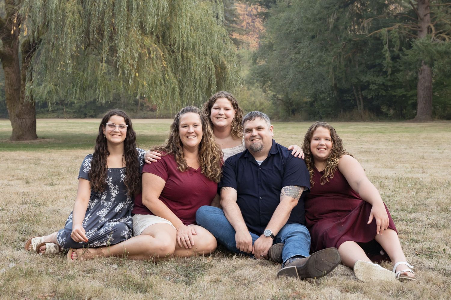Natural light family portrait featuring parents and teens in a peaceful park setting.