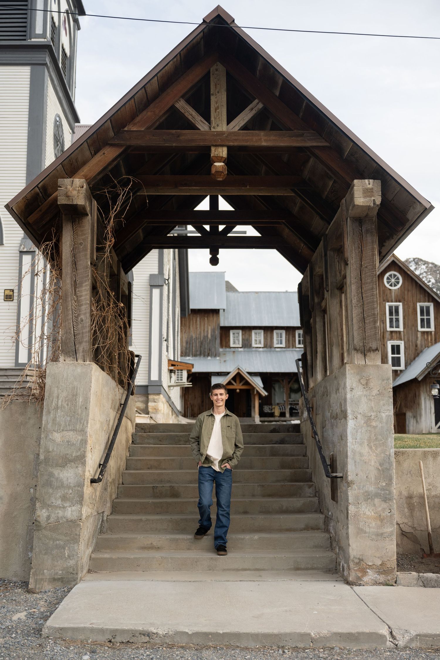 High school senior walking beneath a rustic wooden pavilion during a creative outdoor senior photography session in Utah.