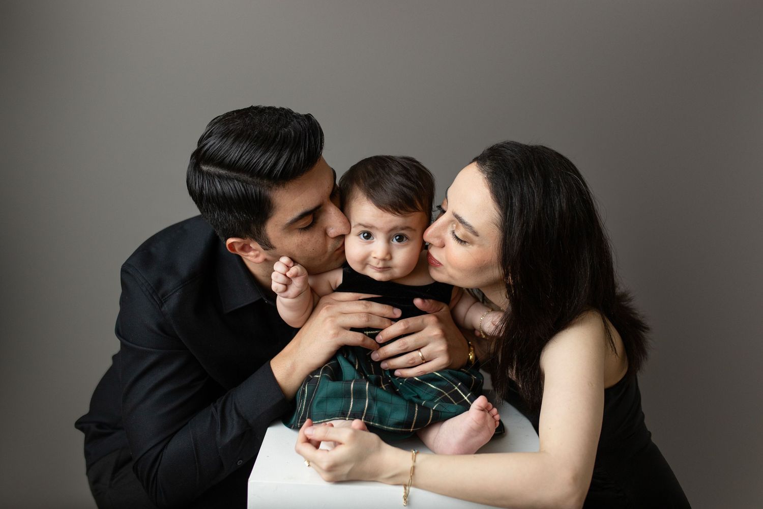 Intimate family portrait session on white background in studio setting.
