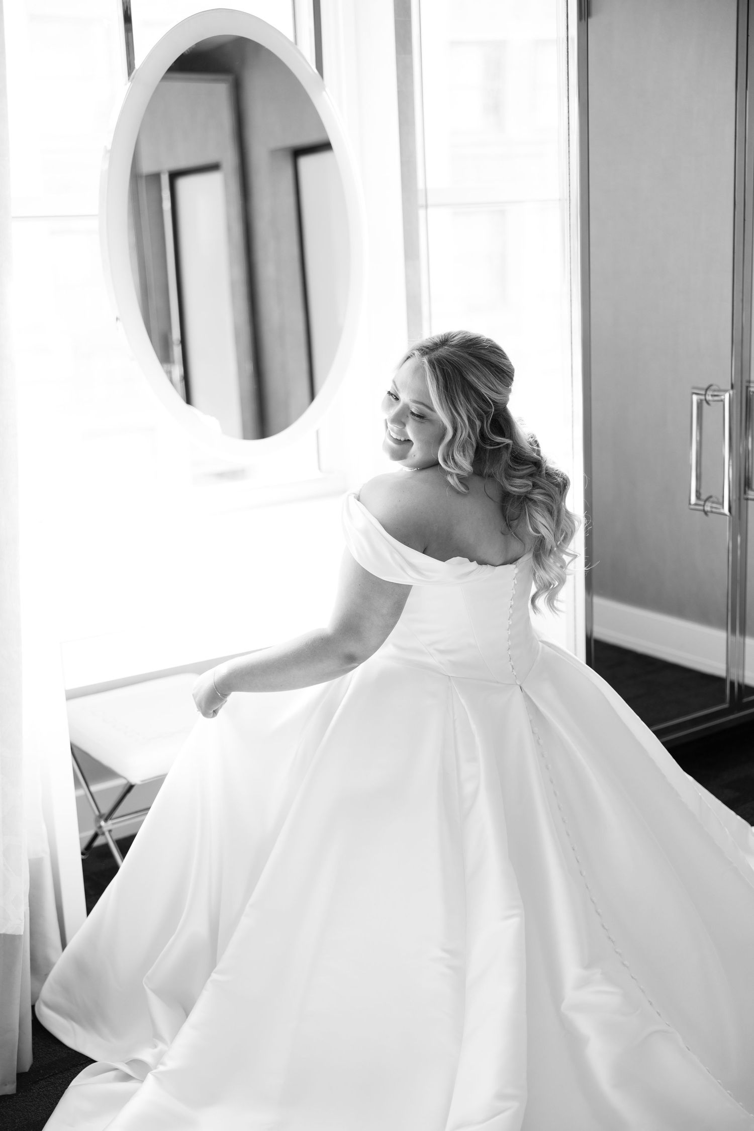 Bride in flowing white wedding dress twirls and spins in an elegant indoor hallway.