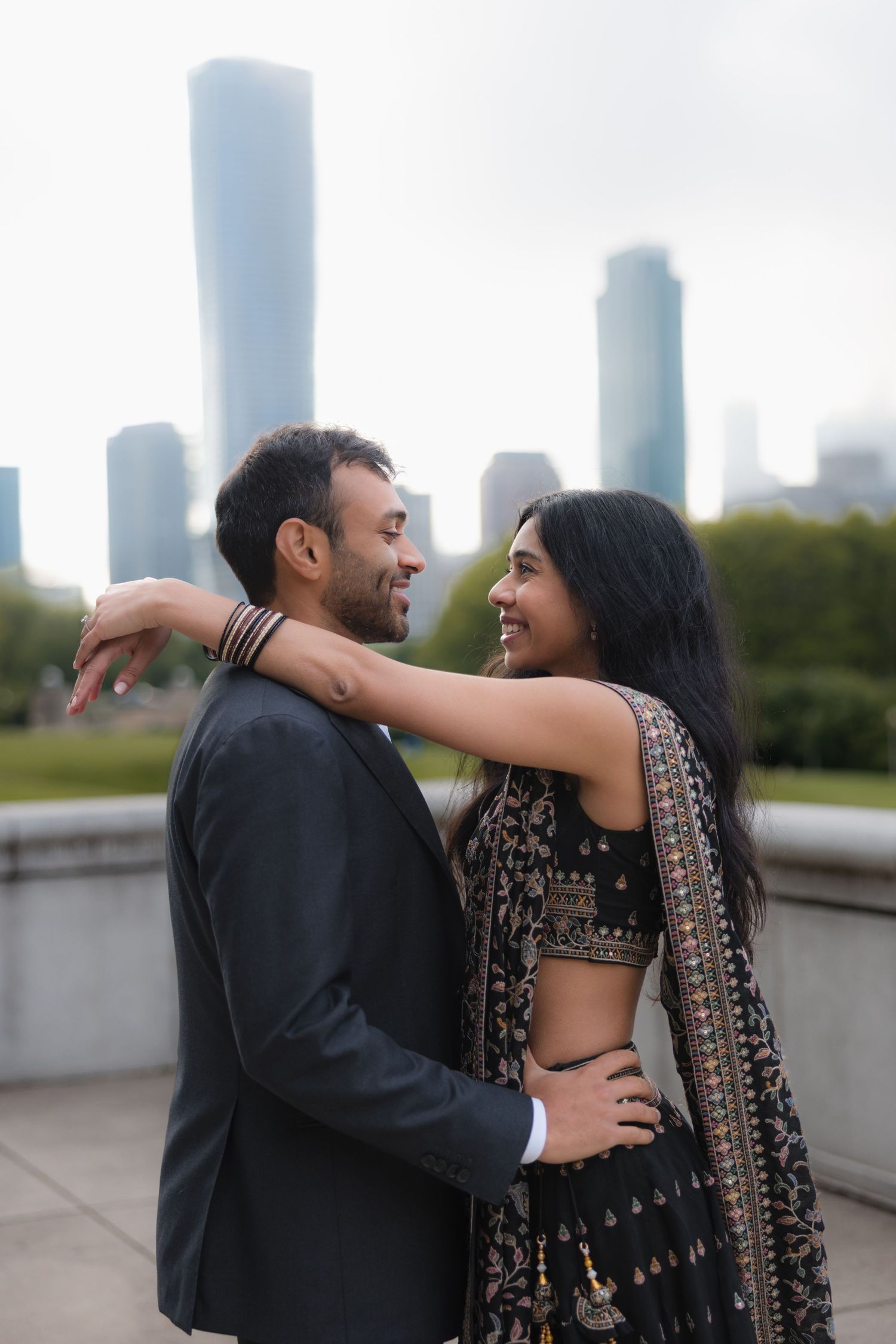 Indian couple in traditional attire embracing with Chicago skyline in the background.