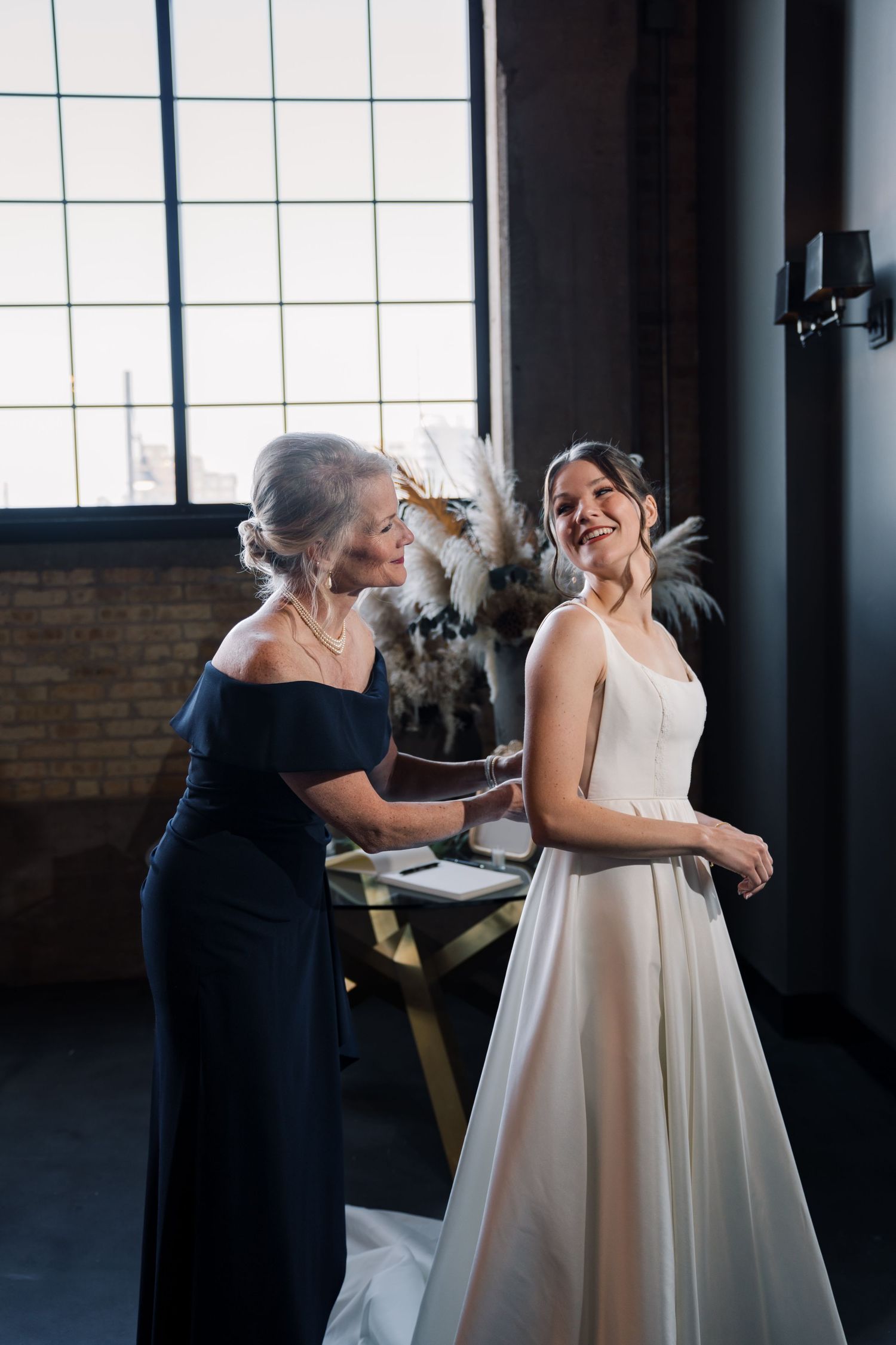 Candid moments of a bride getting ready with helpers in a modern industrial space.